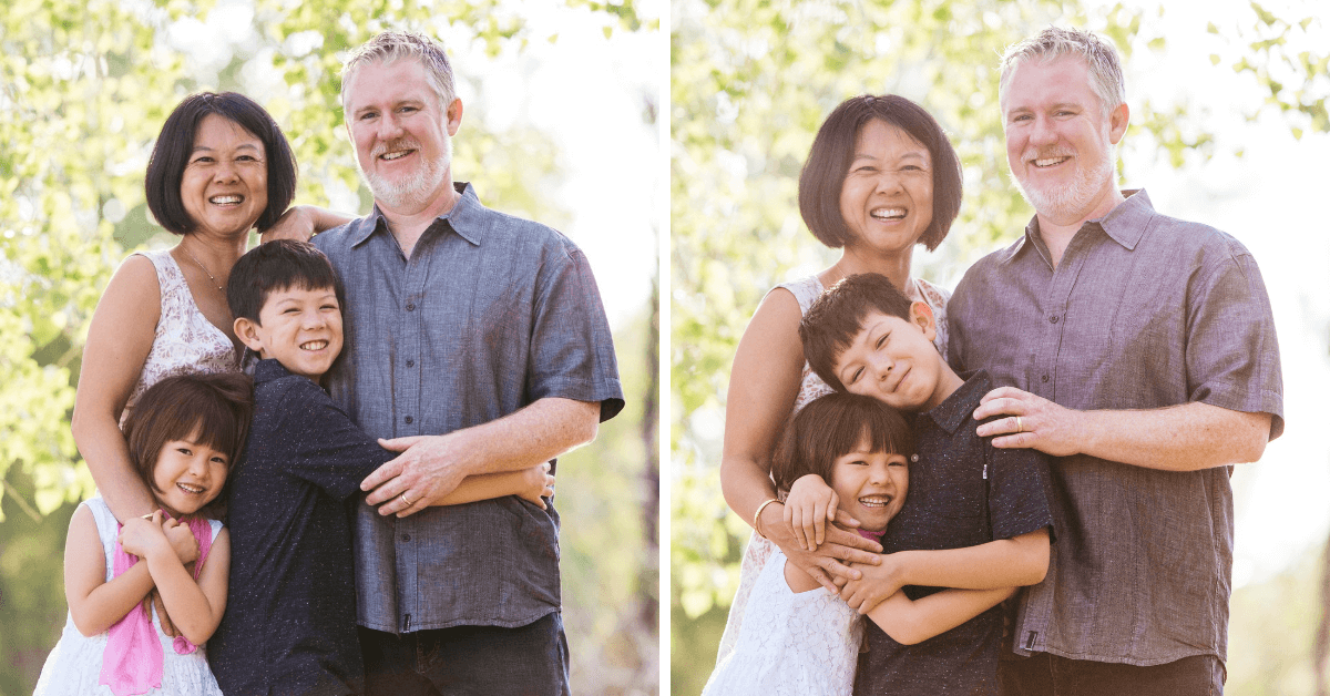 A happy multigenerational family outdoors, smiling and hugging, with trees and sunlight in the background.