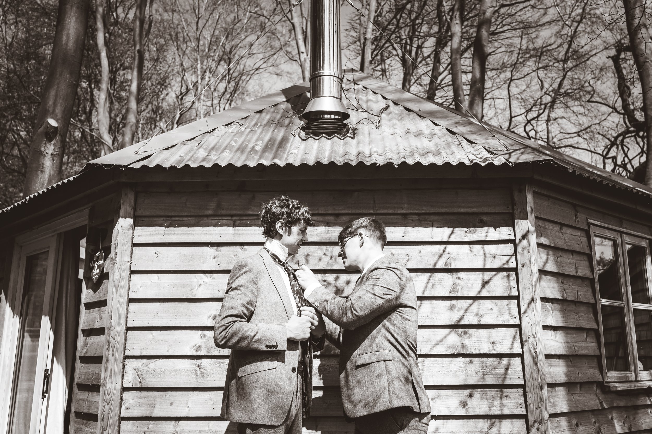 A Best Man helps the Groom to tie his tie outside The Woodpecker cottage