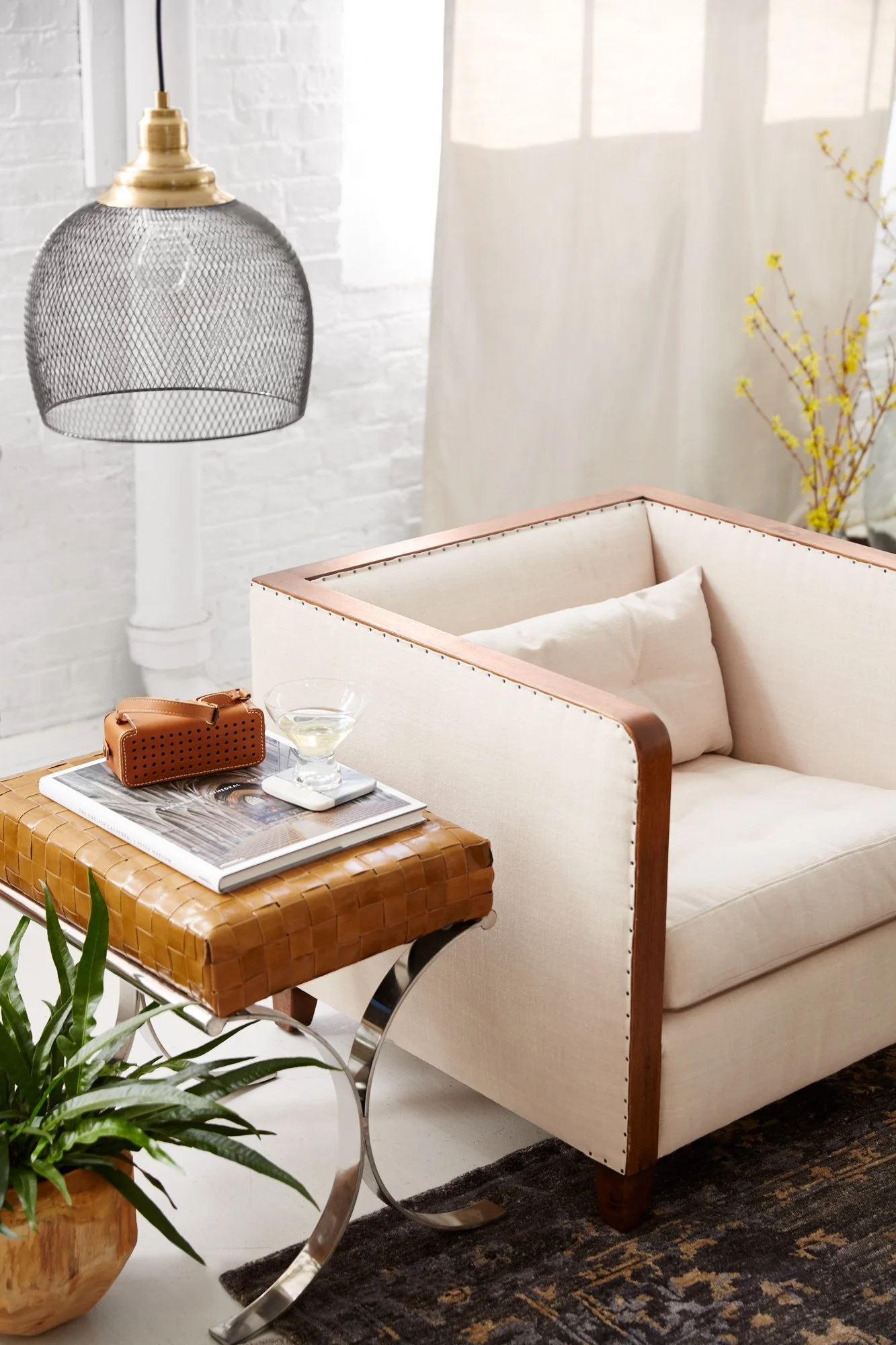 Adam Krauth Photo - Commercial Photography - Boston, MA - Still life - Interior photography. A scene of a living room with a white cushioned armchair, a woven rattan side table with a magazine, a whiskey glass, and a small brown handbag on it. Decor