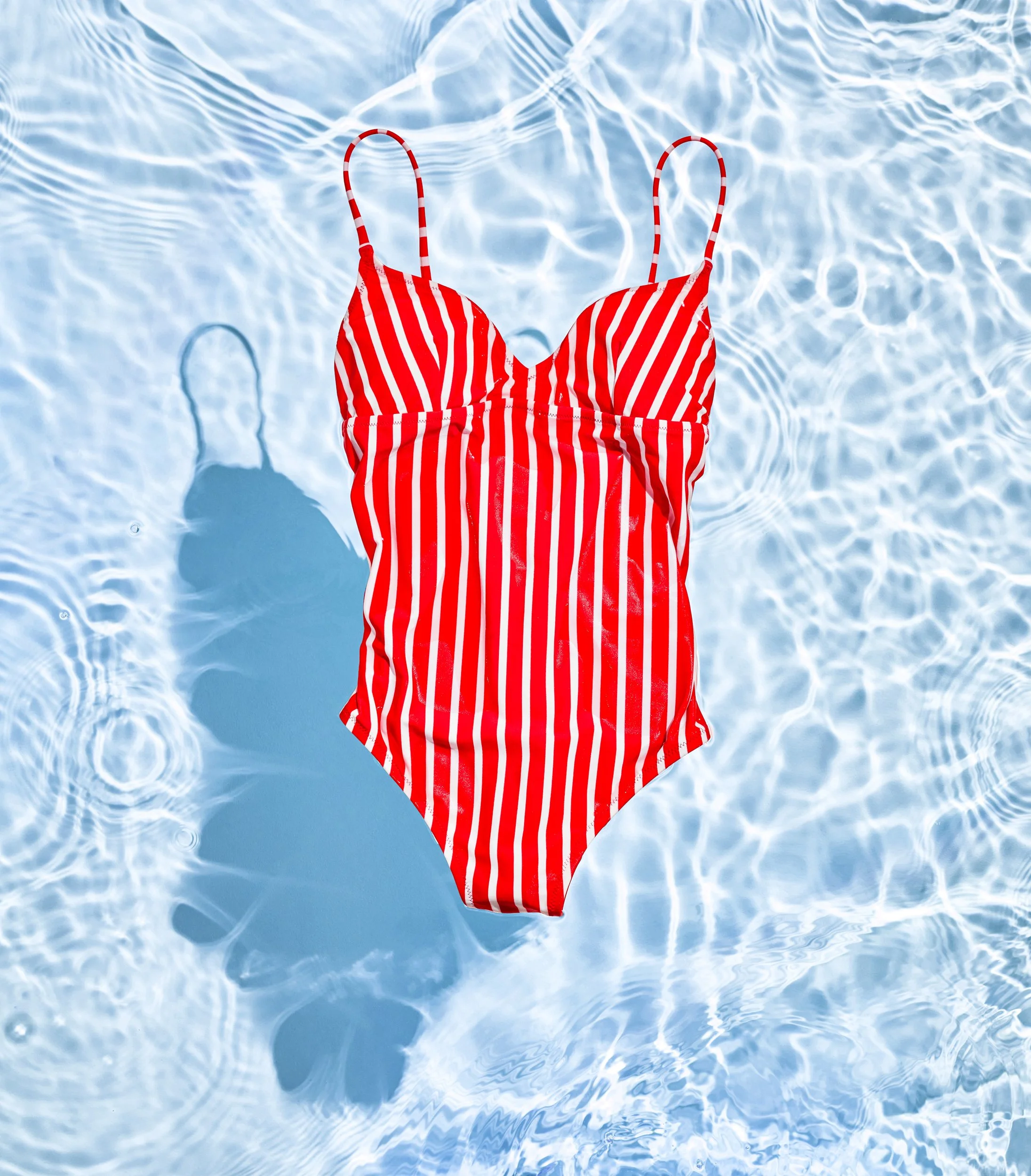 Adam Krauth Photo - Commercial Photography - Boston, MA - Still Life - Product Photography - Red and white striped bikini top floating on a swimming pool with clear blue water.