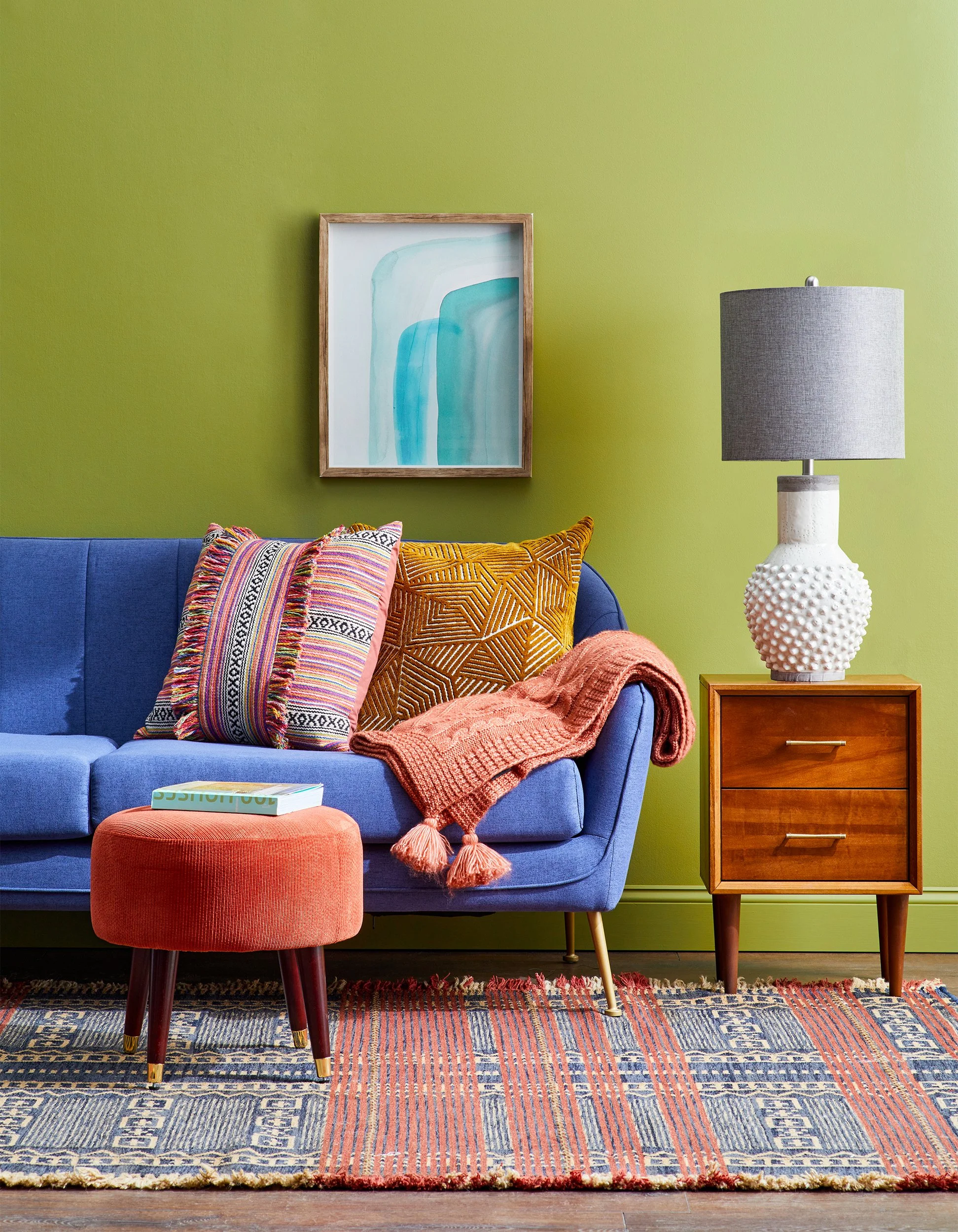 Adam Krauth Photo - Commercial Photography - Boston, MA - Still life - Interior photography. A scene with a living room with a blue sofa, colorful pillows, a side table with a lamp, a green accent wall, and a patterned area rug.