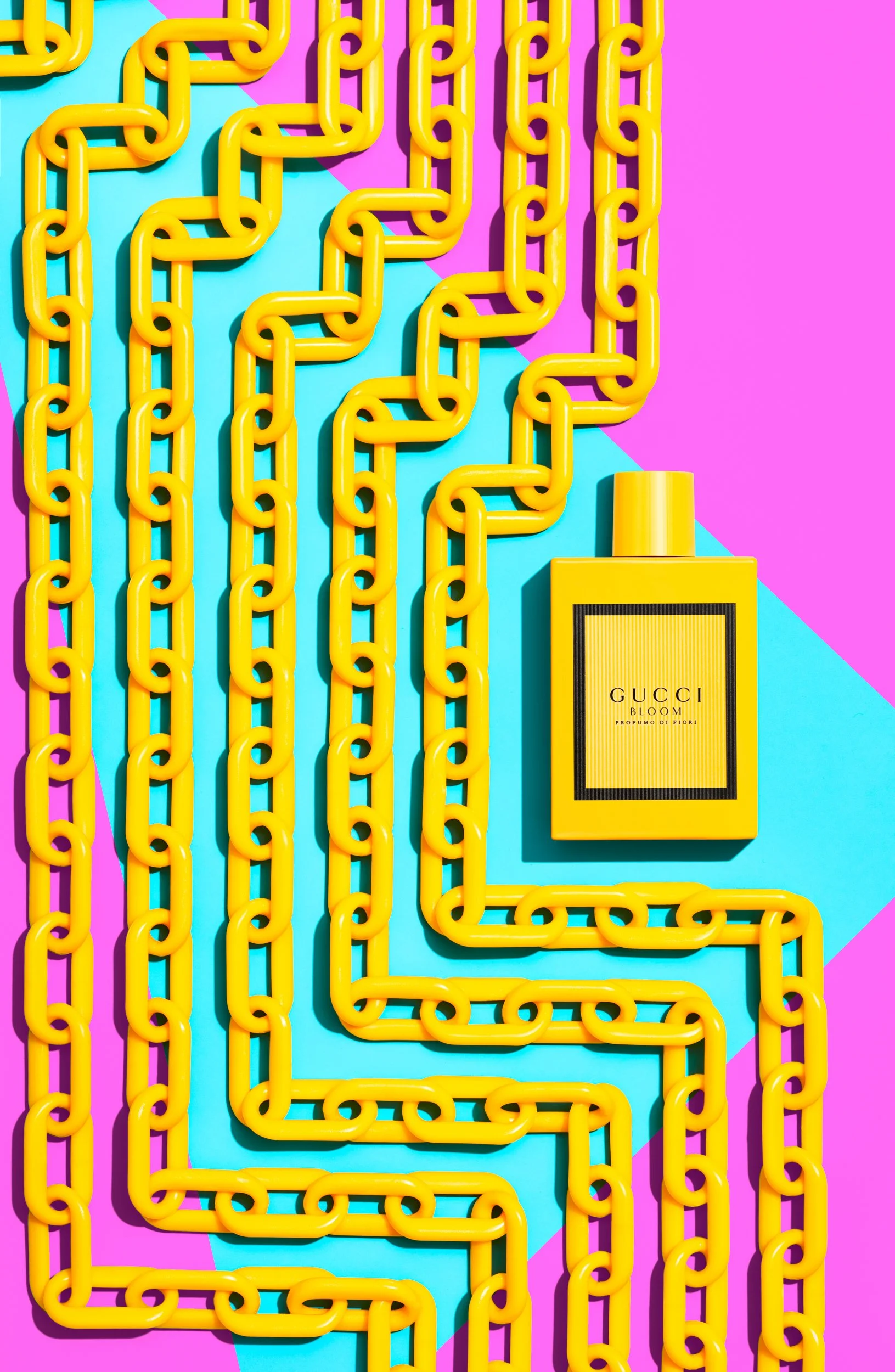 Adam Krauth Photo - Commercial Photography - Boston, MA - Still Life - Product Photography - Yellow plastic chains arranged in a pattern on a colorful pink and blue background with a yellow Gucci Bloom perfume bottle. Fragrance Photography 