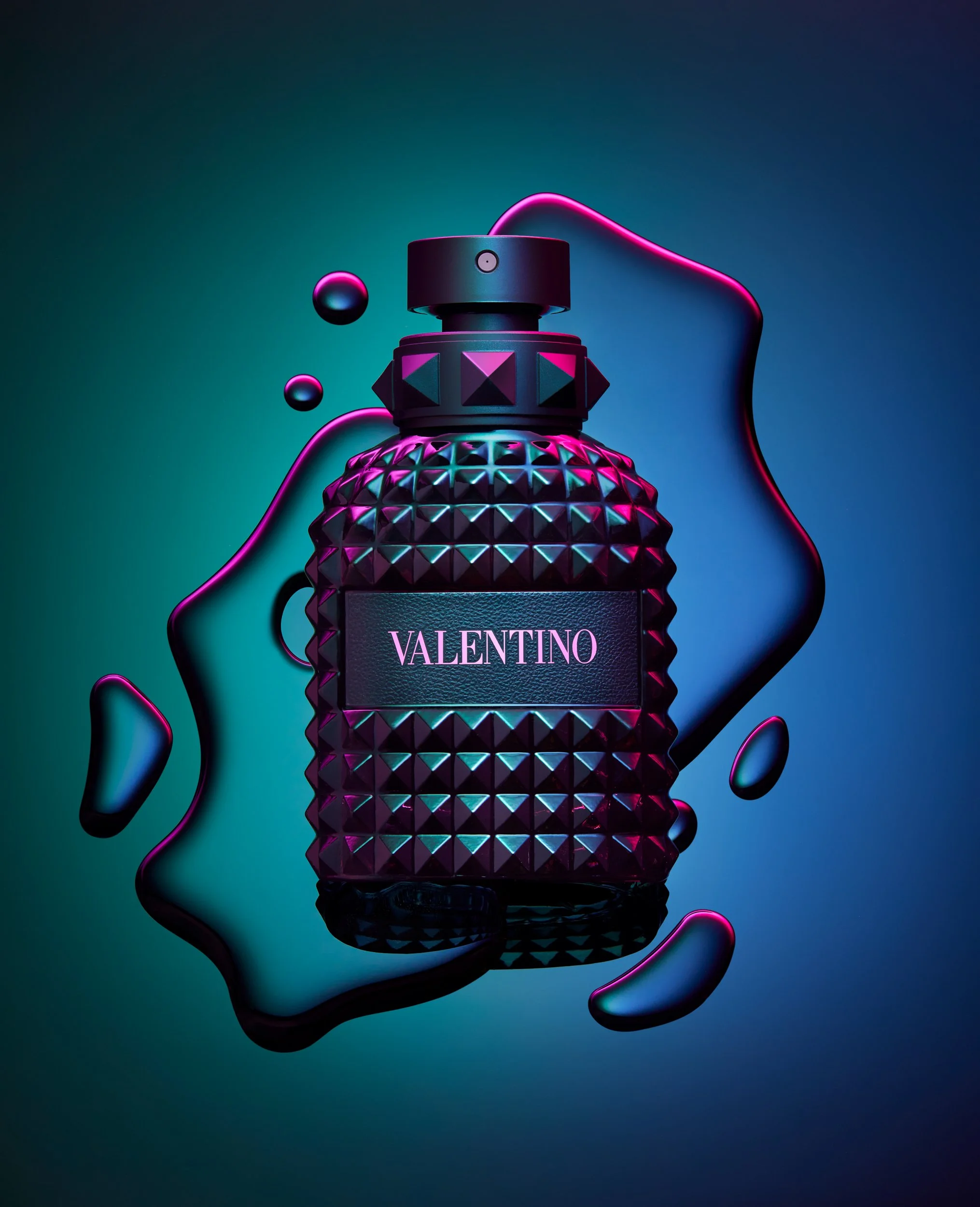 Adam Krauth Photo - Commercial Photography - Boston, MA - Still Life - Product Photography - A Valentino perfume bottle with a textured, geometric surface is displayed against a dark gradient background with pink and teal toned lighting. Fragrance Va