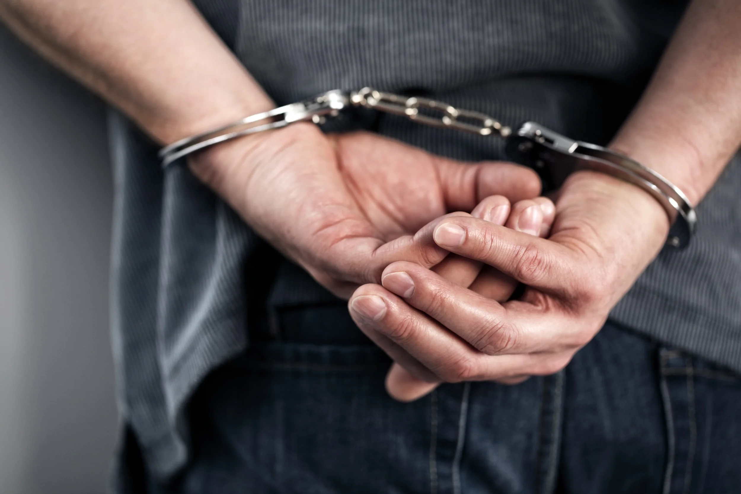 Hands behind back in handcuffs.