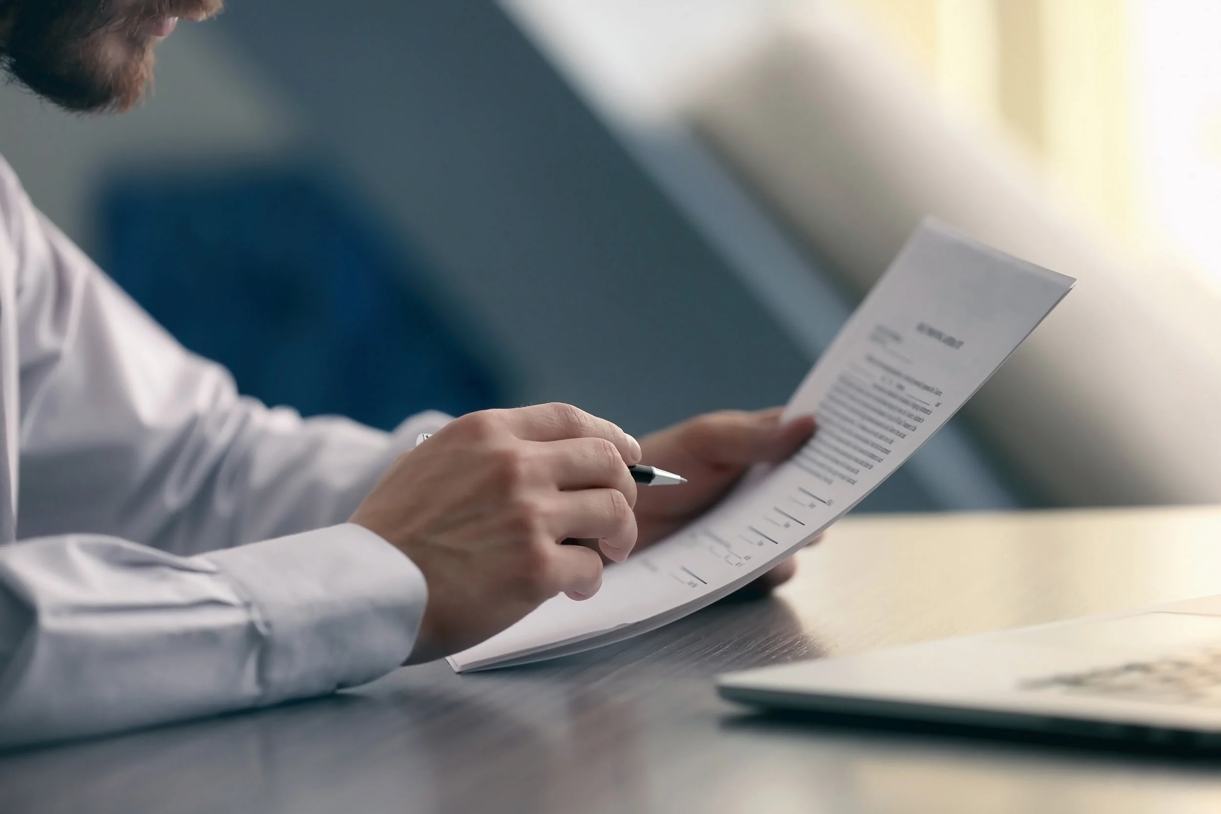 Man reading a contract with pen in hand.