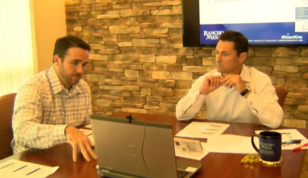 Chase Hixson and Sam Brown sitting at a table looking at a laptop screen.