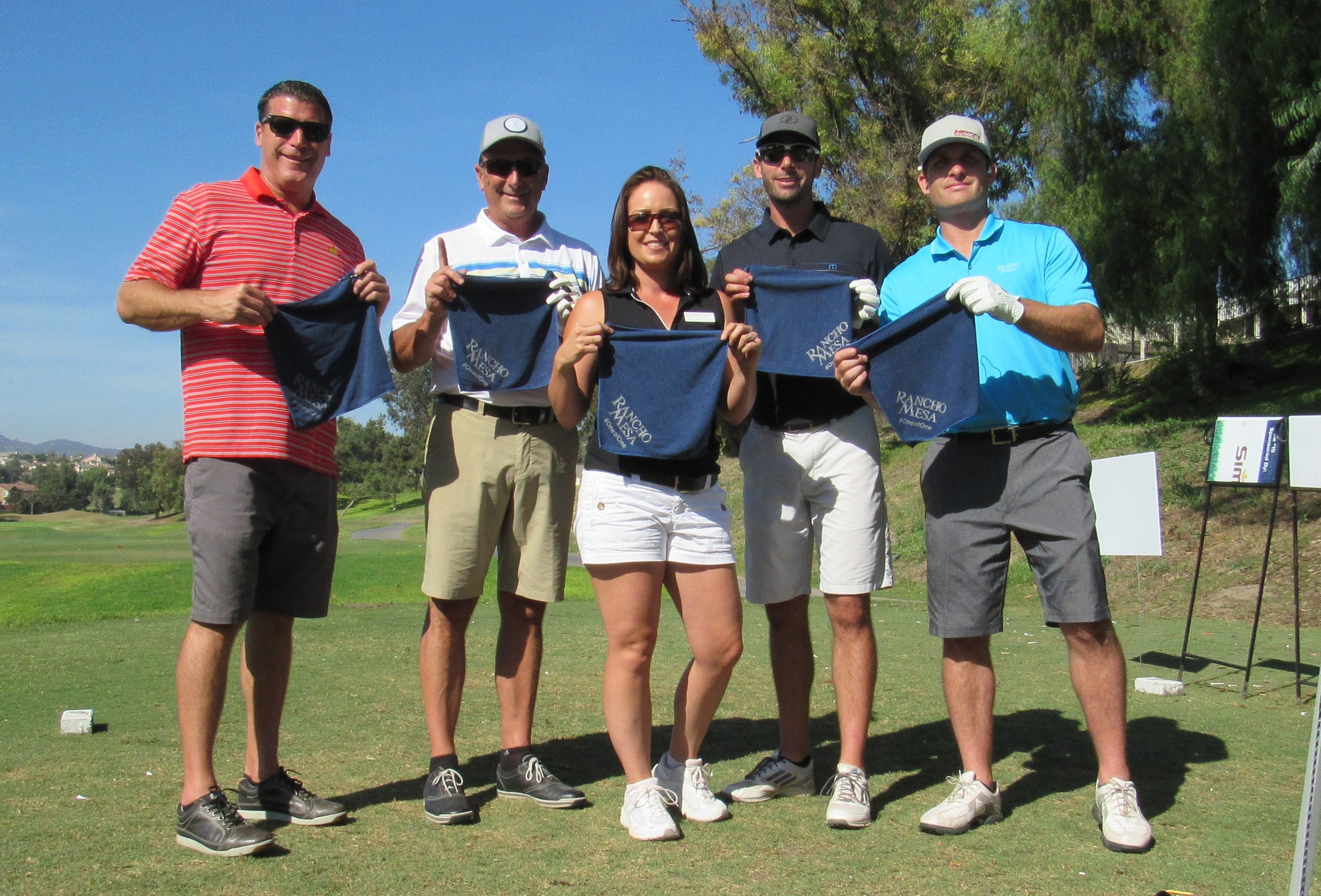 Sam Clayton, Dave Garcia, Alyssa Burley, Drew Garcia, and Kevin Howard holding Rancho Mesa golf towels on the course.