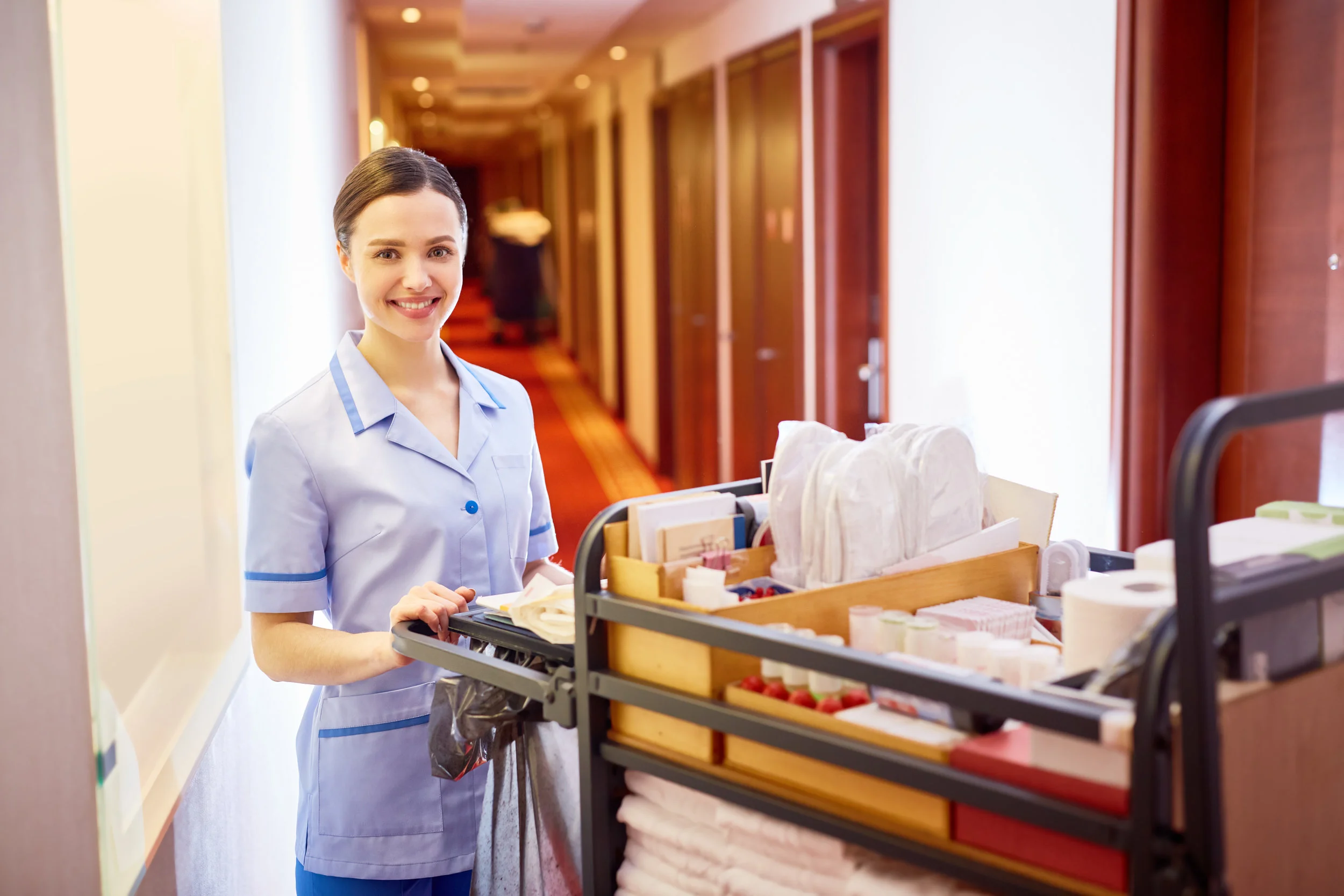 Women standing in hallway with a cleaning cart.