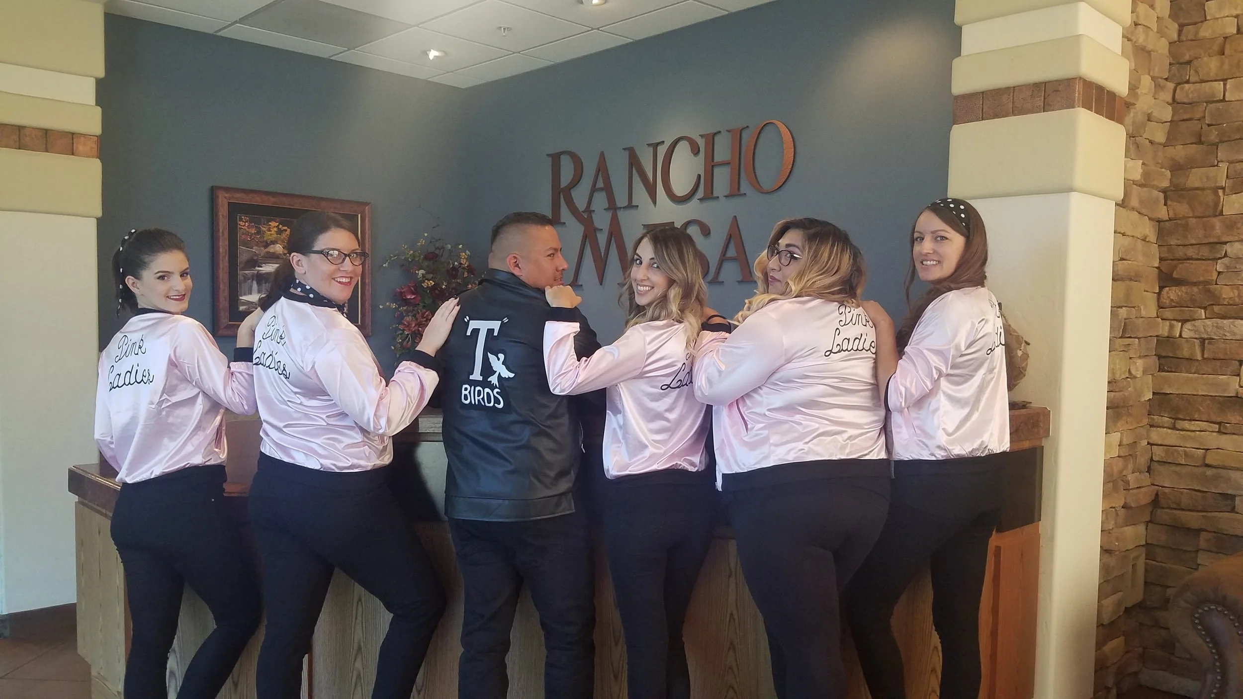 Five Pink Ladies and one T-Bird (Greaser) turned around to show the back of their jackets