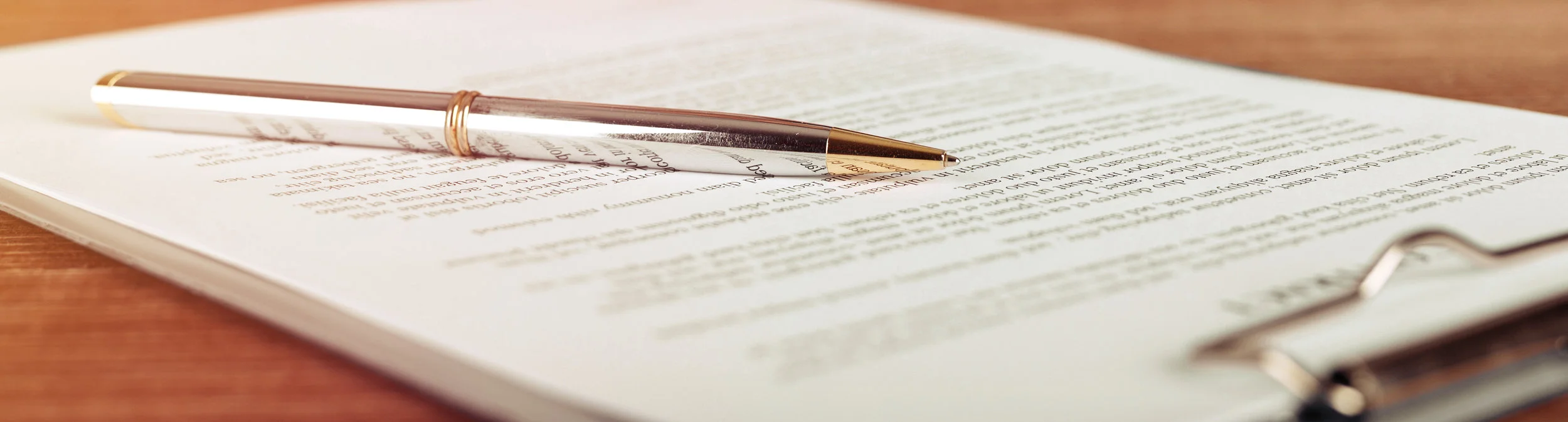 A pen laying on a letter on a clipboard on a table.