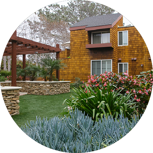 Well landscaped yard with a house in the background and flowers and plants in the forground.