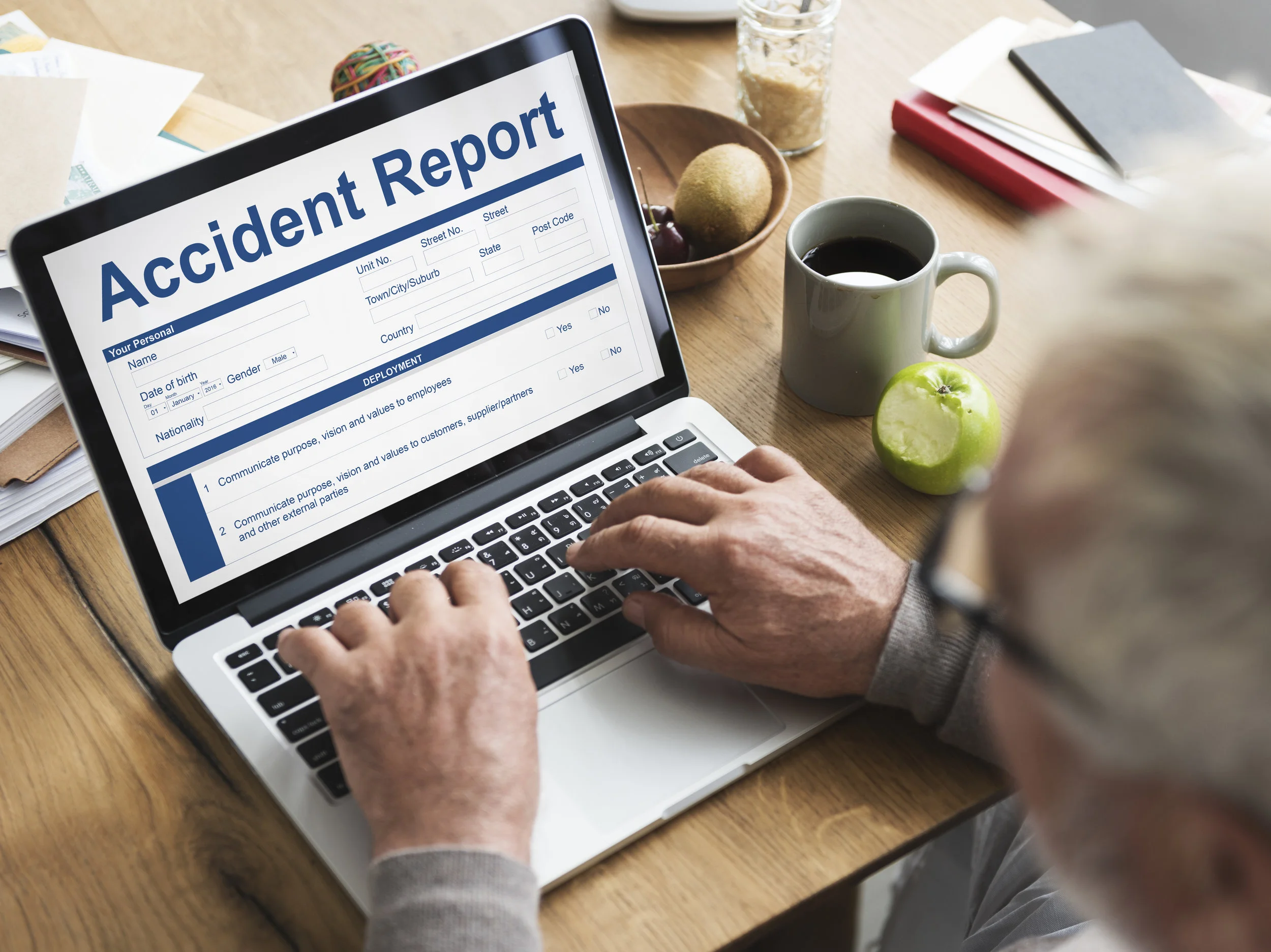 Man sitting at a laptop with an Accident Report on the screen.