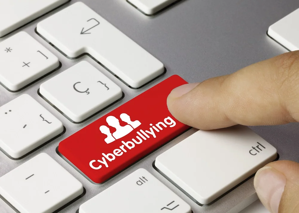 Image of red “Cyberbullying” key on keyboard being pressed by finger.