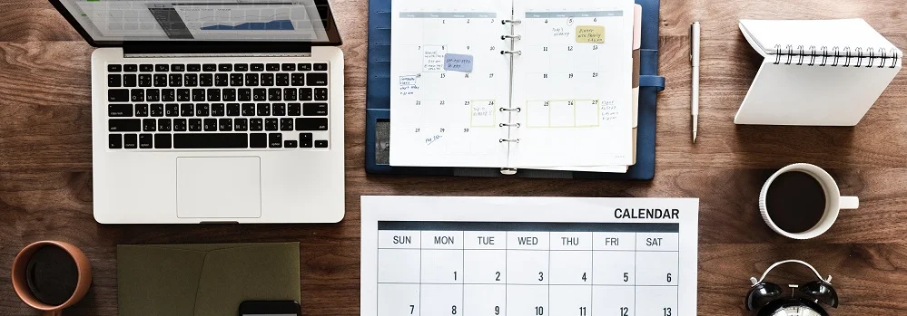 Image of calendar, planner, laptop, and coffee on desk