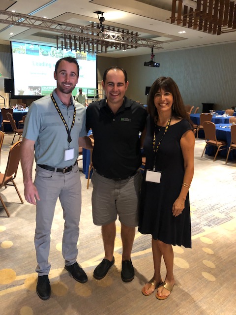 Drew Garcia, a man and Margaret Hartmann smiling in the ballroom at Leaders Forum