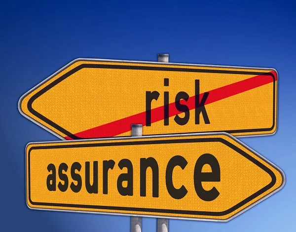 “Risk” and “Assurance” yellow street signs pointing opposite directions. “Risk” sign has a red line through it.