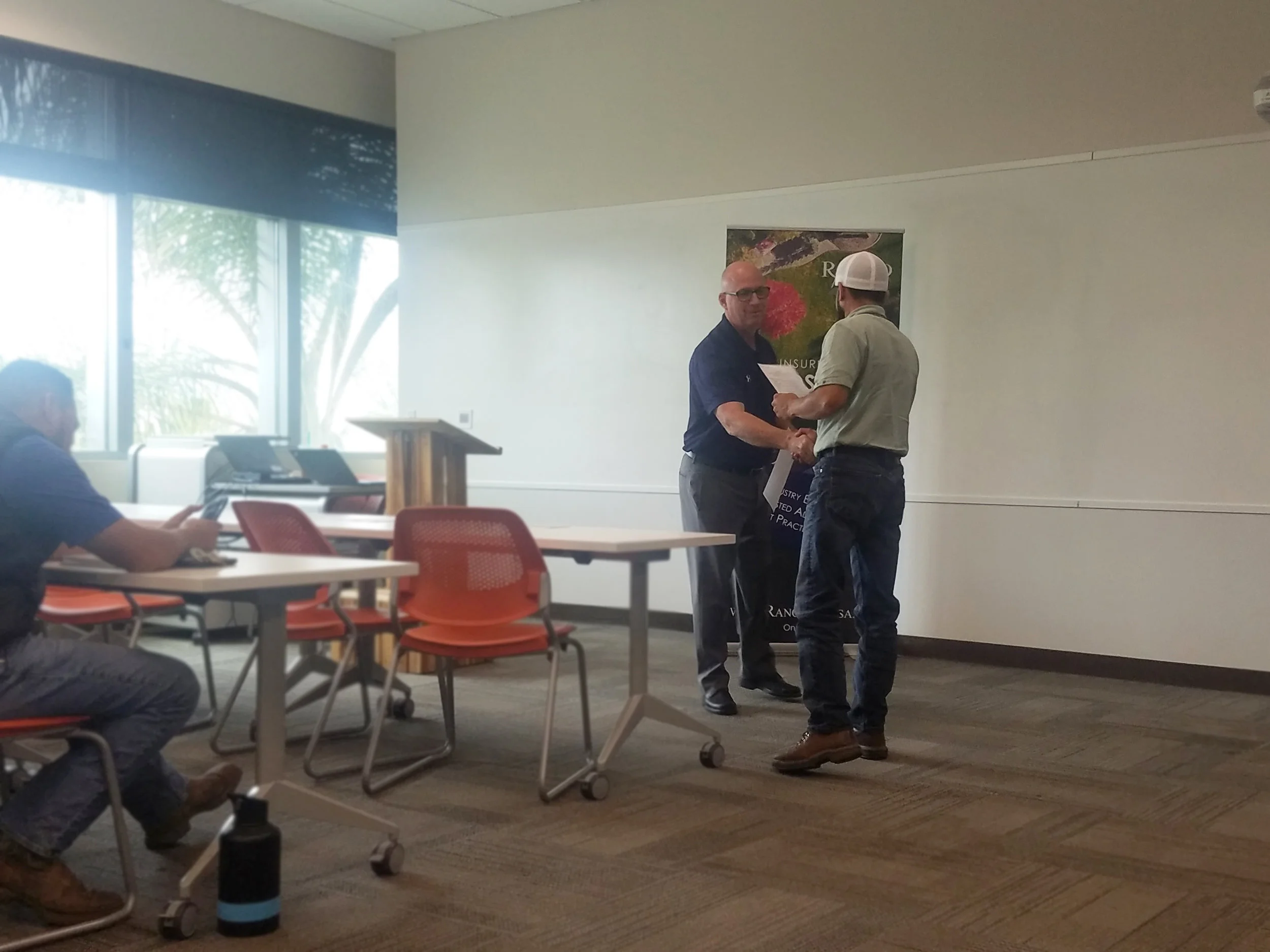 Image of Steve shaking hands and presenting to certificate to a class participant.