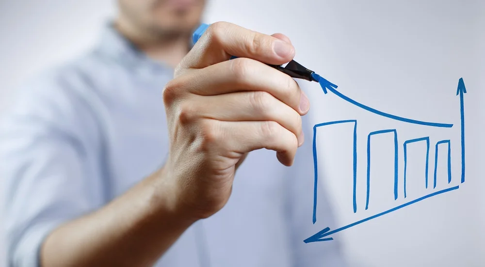 Image of a male hand drawing a graph using a blue marker.
