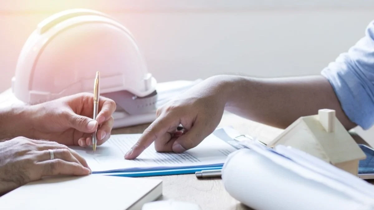 Filling out contract papers with construction hat on desk.jpg