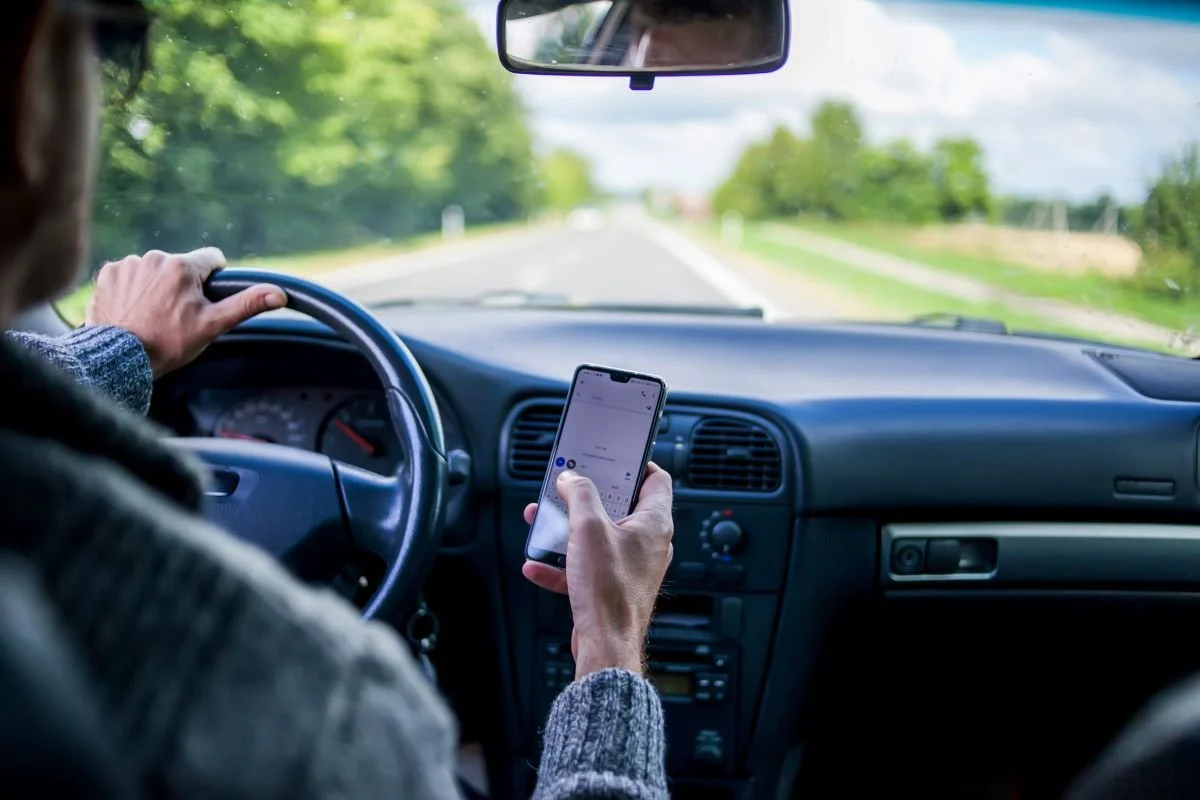 A man useing smartphone while driving in the car.jpg