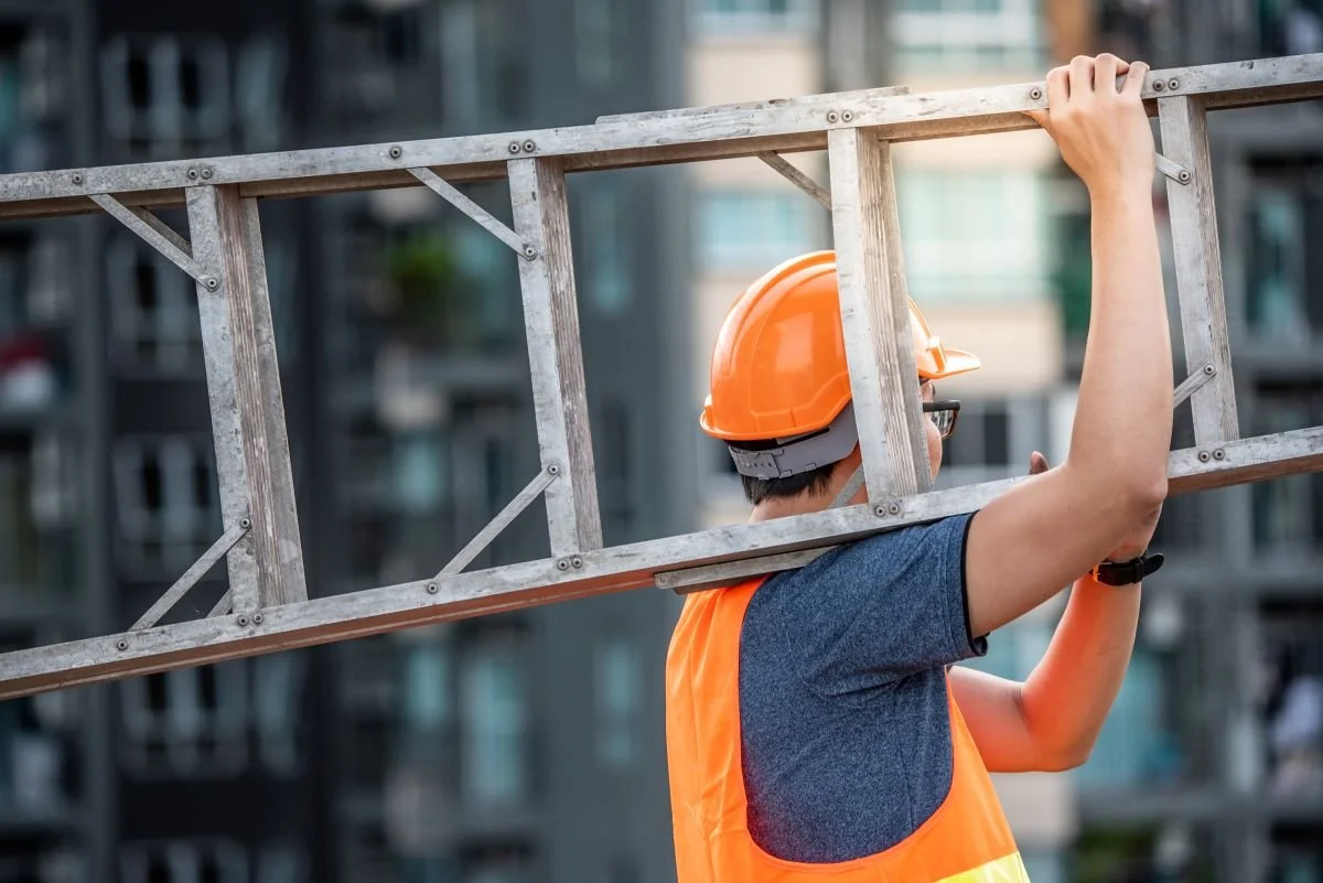 Construction worker carrying a ladder.jpg