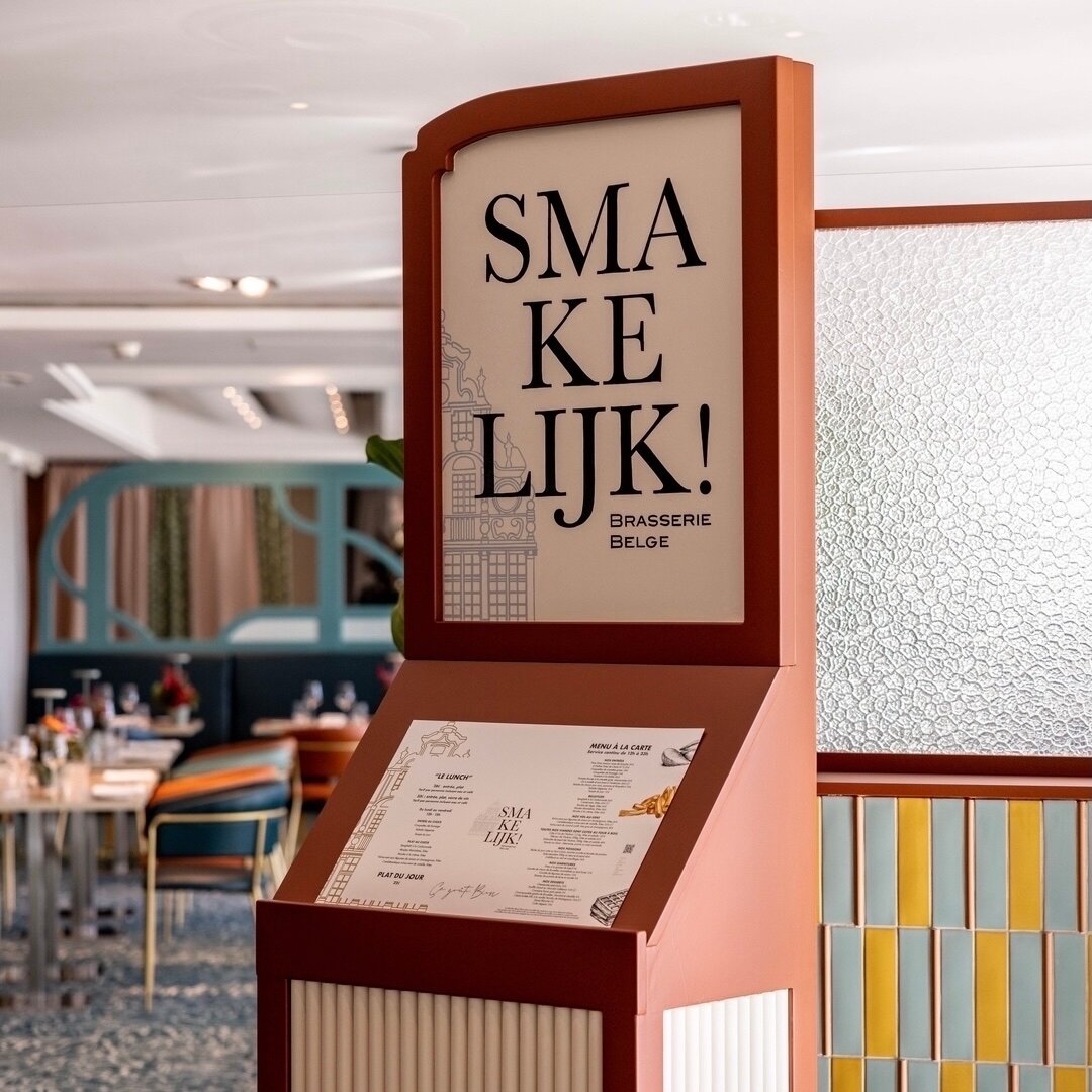 SMAKELIJK ou &ldquo;Bon app&eacute;tit&rdquo; en flamand 🇧🇪 

Une enseigne porte-menu dessin&eacute;e pour attirer l&rsquo;&oelig;il des clients de l&rsquo;h&ocirc;tel depuis le lobby, et asseoir l&rsquo;identit&eacute; du restaurant. 
Le dessin re