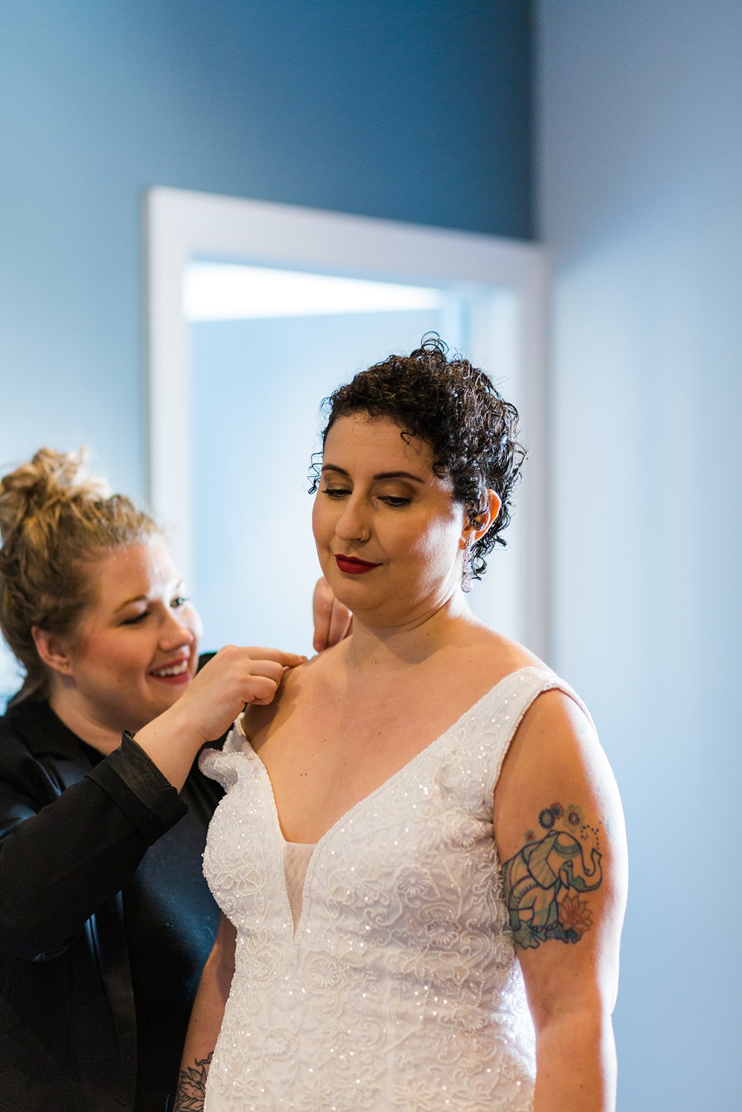  Photo of Burst wedding planner helping queer non traditional bride into their dress 