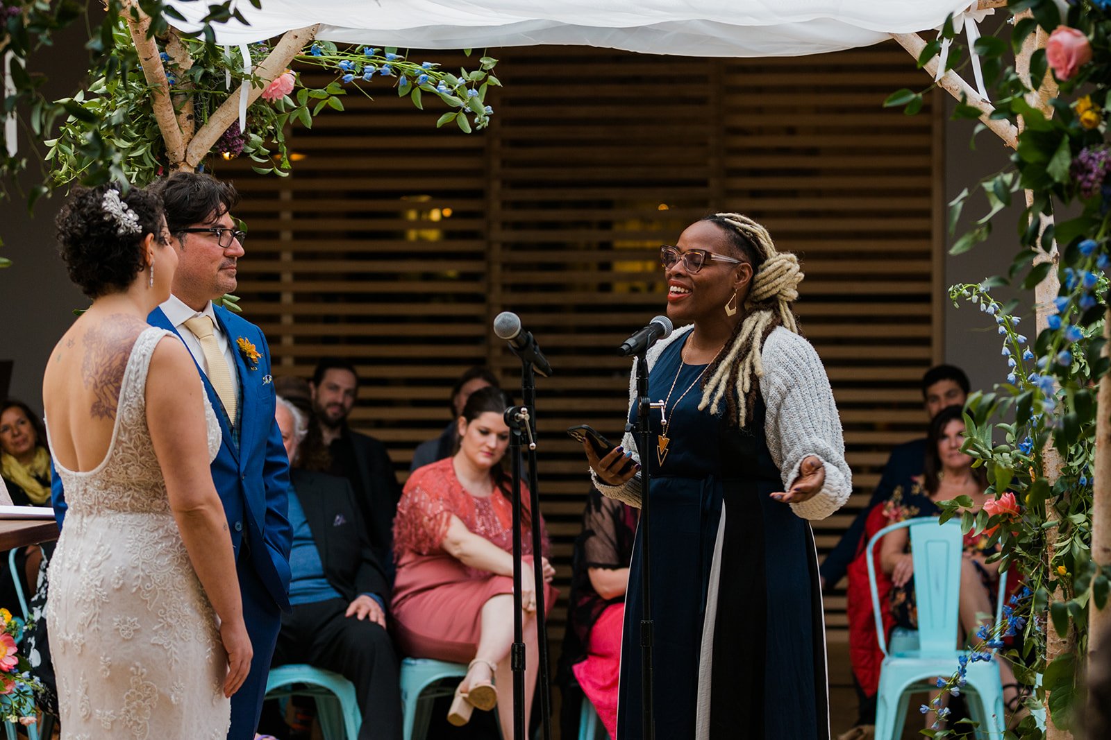  Candid, documentary photo of a friend performing a song to the bride and groom chupah during their nontraditional Jewish and Venezuelan wedding ceremony in the round at The Joinery Chicago an Industrial loft wedding venue In Logan Square. 