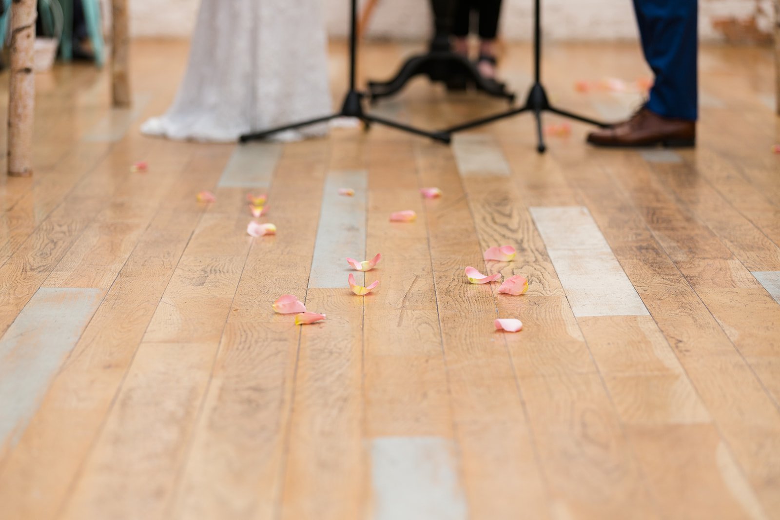  Candid, documentary detail photo of the bride and grooms feet with flower petals on the floor during their nontraditional Jewish and Venezuelan wedding ceremony in the round at The Joinery Chicago an Industrial loft wedding venue In Logan Square. 