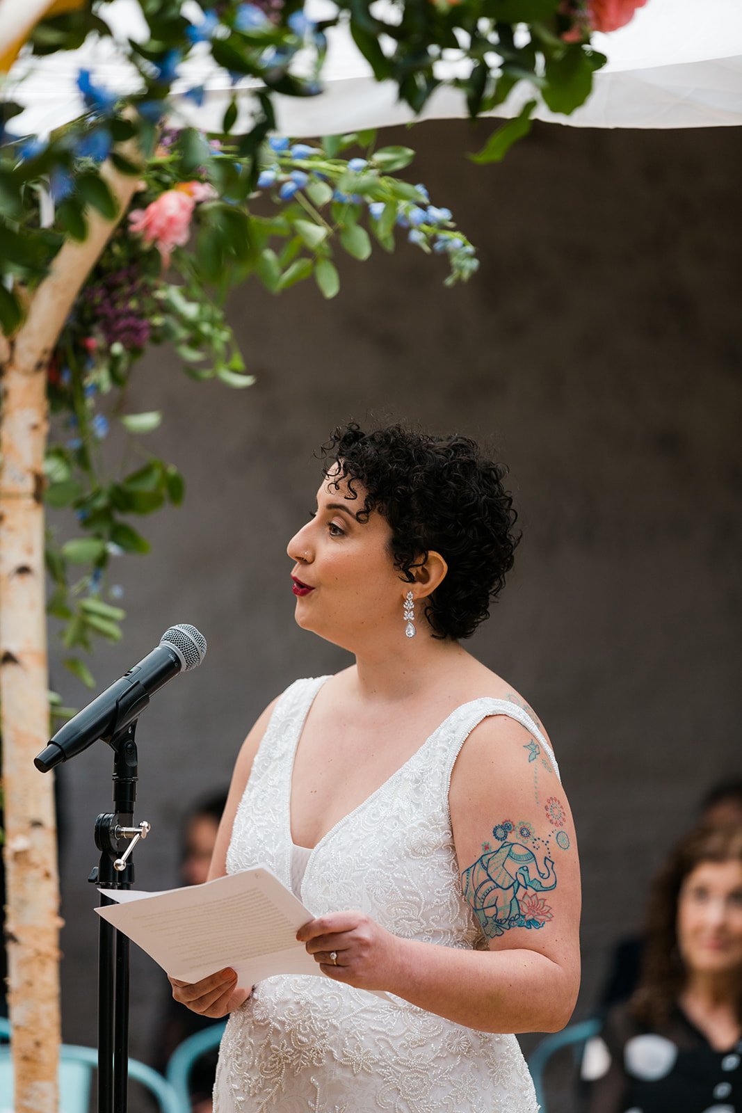  Candid, documentary photo of the bride under chupah during their nontraditional Jewish and Venezuelan wedding ceremony in the round at The Joinery Chicago an Industrial loft wedding venue In Logan Square. 