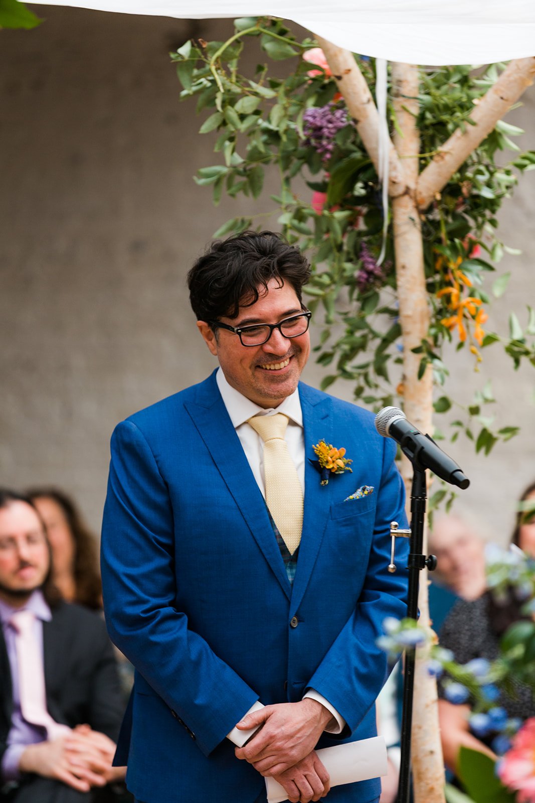  Candid, documentary photo of the groom under chupah during their nontraditional Jewish and Venezuelan wedding ceremony in the round at The Joinery Chicago an Industrial loft wedding venue In Logan Square. 