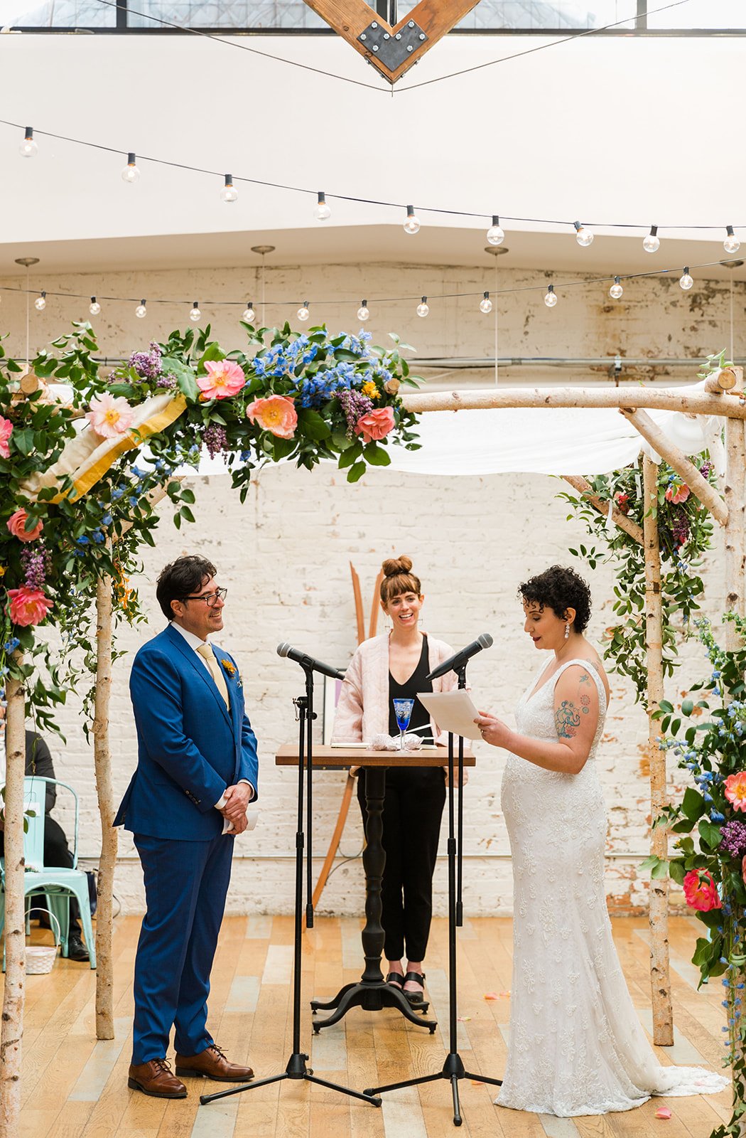  Candid, documentary photo of the couple reading their vows under chupah during their nontraditional Jewish and Venezuelan wedding ceremony in the round at The Joinery Chicago an Industrial loft wedding venue In Logan Square. 
