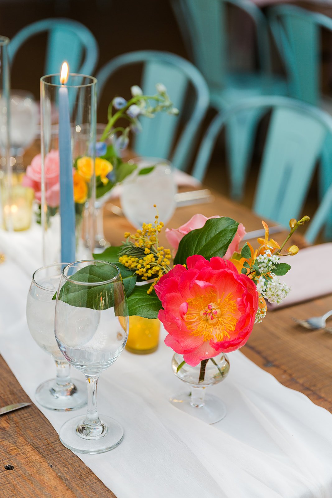  Documentary detail of wedding table decor with bright florals, tall colorful candles and airy white linens at nontraditional Jewish and Venezuelan wedding  at The Joinery Chicago an Industrial loft wedding venue In Logan Square. Great wedding decor 