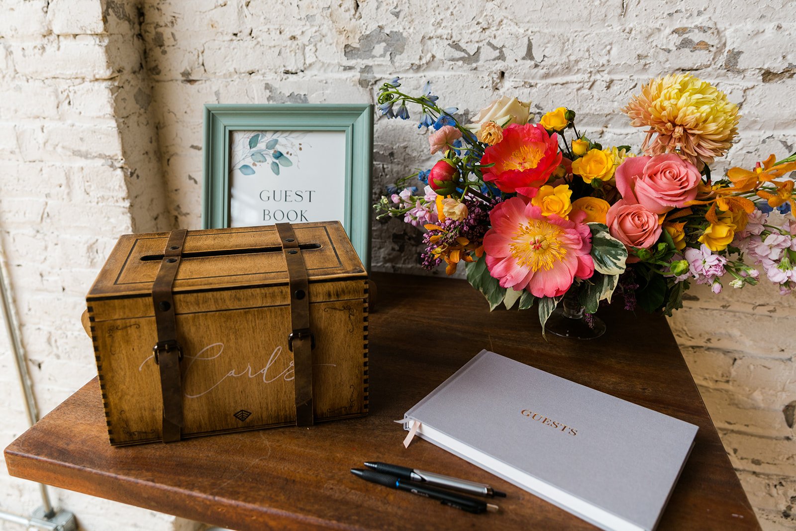  Documentary detail of wedding decor, guest book, card box and bright florals at nontraditional Jewish and Venezuelan wedding  at The Joinery Chicago an Industrial loft wedding venue In Logan Square. 