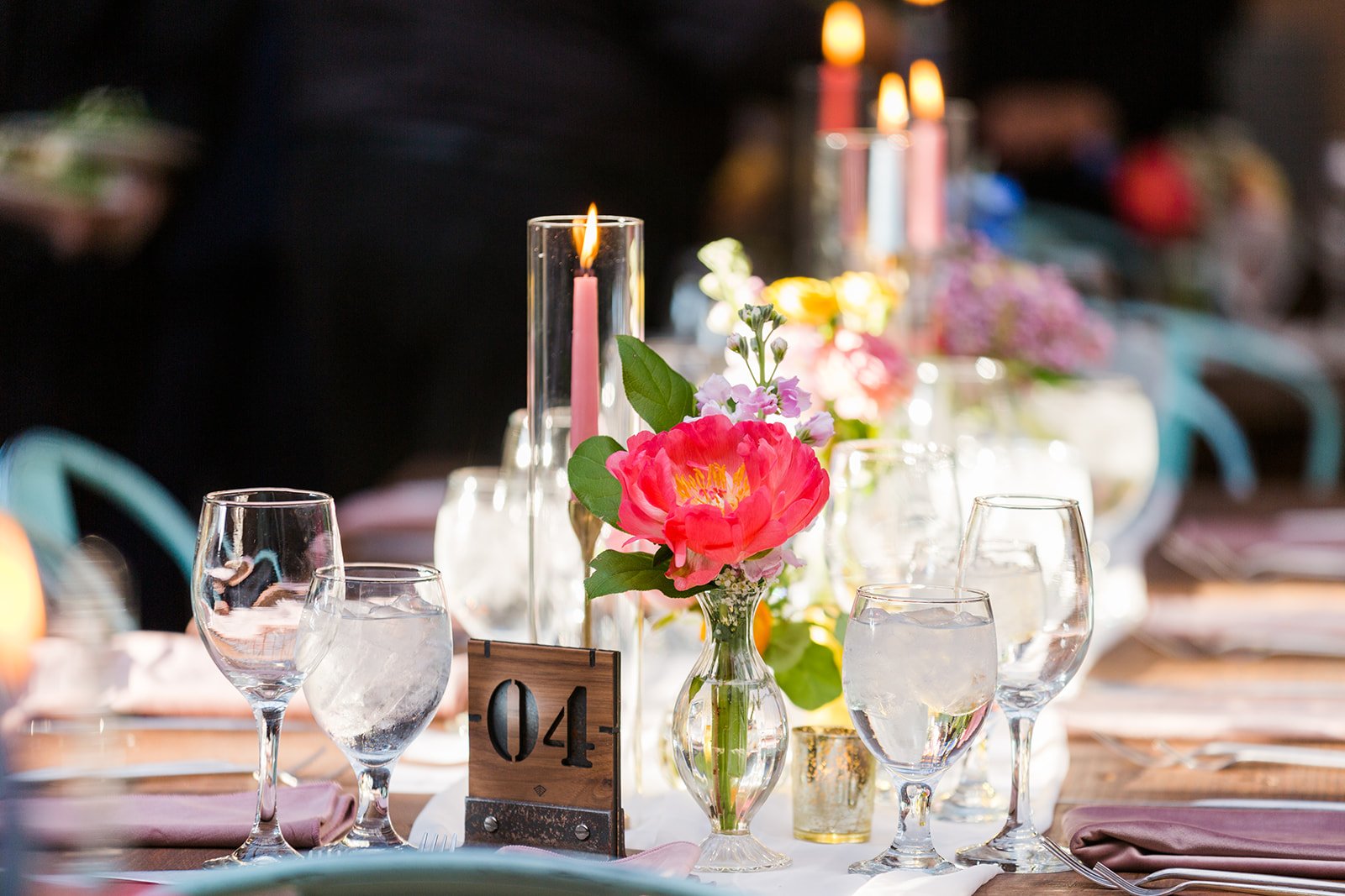  Documentary detail of wedding table decor with bright florals, tall colorful candles and airy white linens at nontraditional Jewish and Venezuelan wedding  at The Joinery Chicago an Industrial loft wedding venue In Logan Square. Great wedding decor 