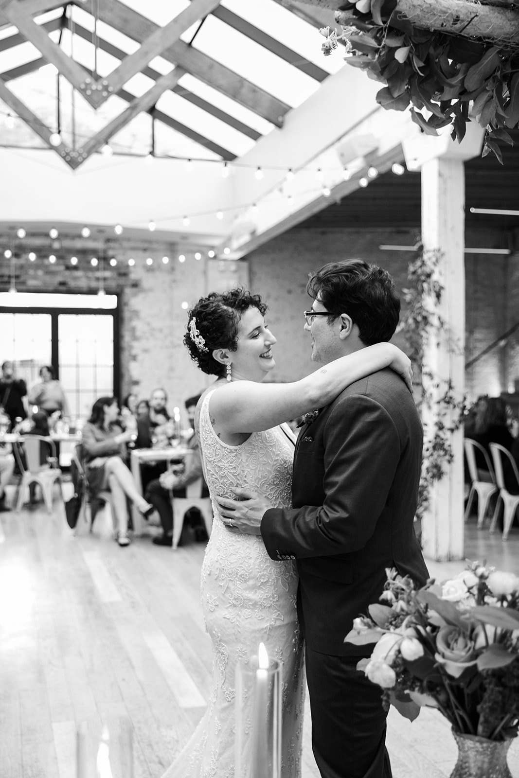 Black and white Documentary candid photo of bride and groom during first dance nontraditional Jewish and Venezuelan wedding at The Joinery Chicago an Industrial loft wedding venue In Logan Square.  