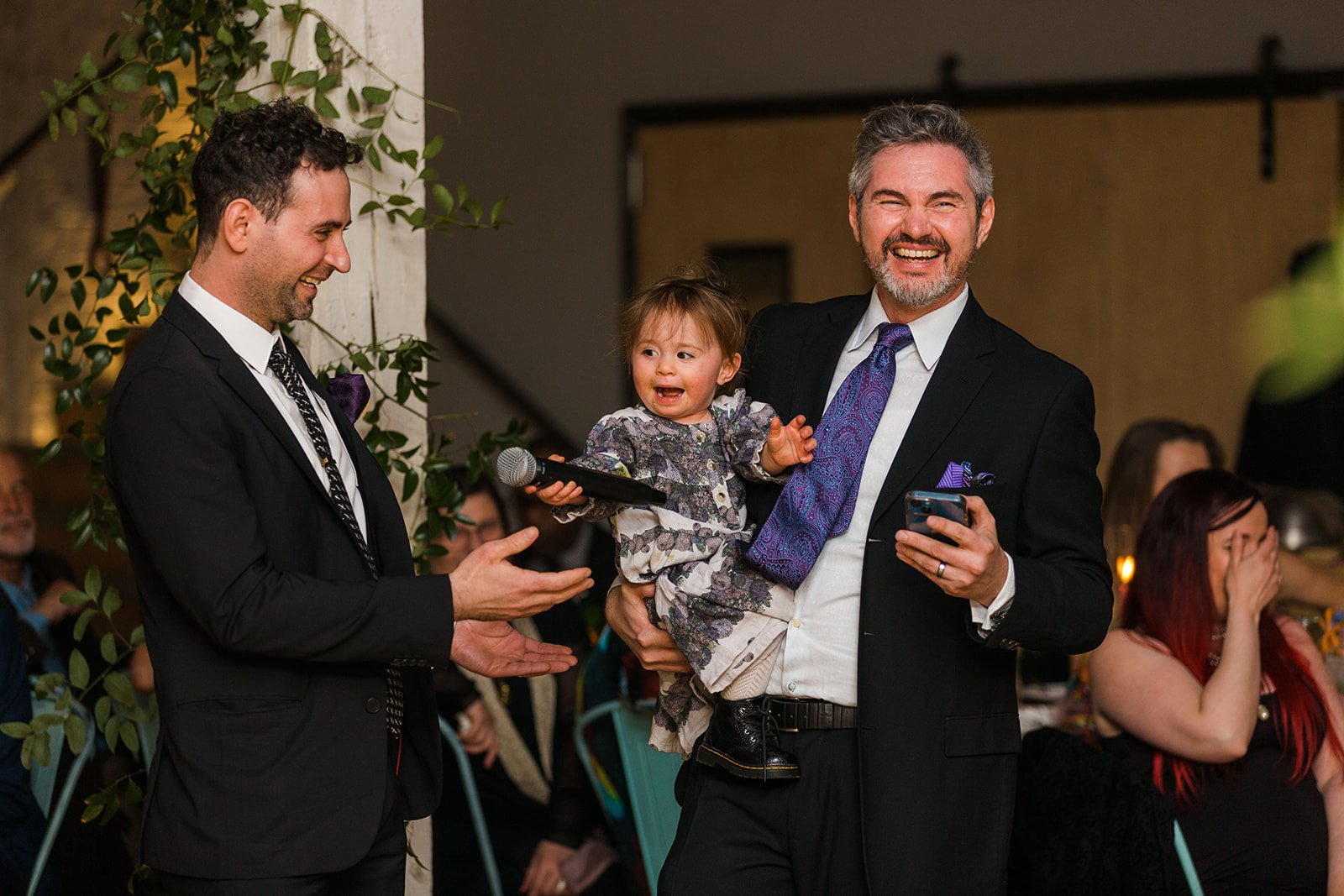  Documentary candid photo of bride’s brothers and niece giving a toast during the reception at nontraditional Jewish and Venezuelan wedding at The Joinery Chicago an Industrial loft wedding venue In Logan Square.  