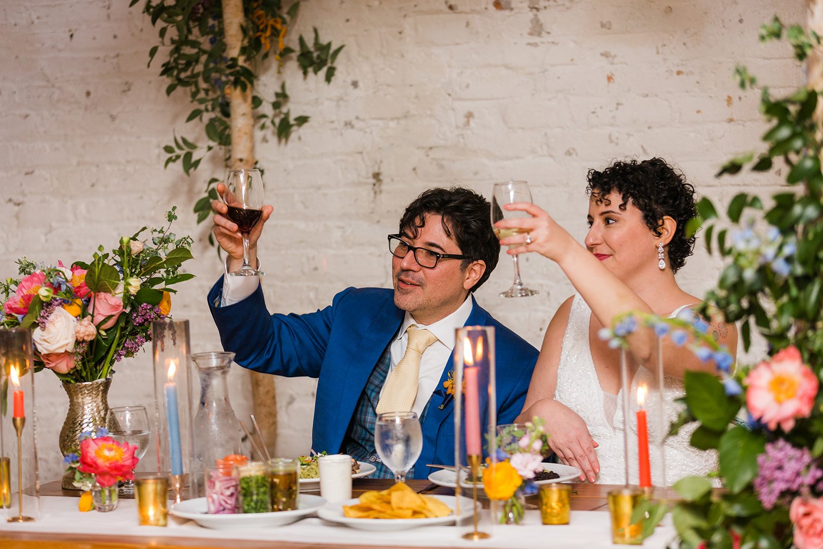  Documentary candid photo of bride and groom cheersing to a toast during the reception at nontraditional Jewish and Venezuelan wedding at The Joinery Chicago an Industrial loft wedding venue In Logan Square.  