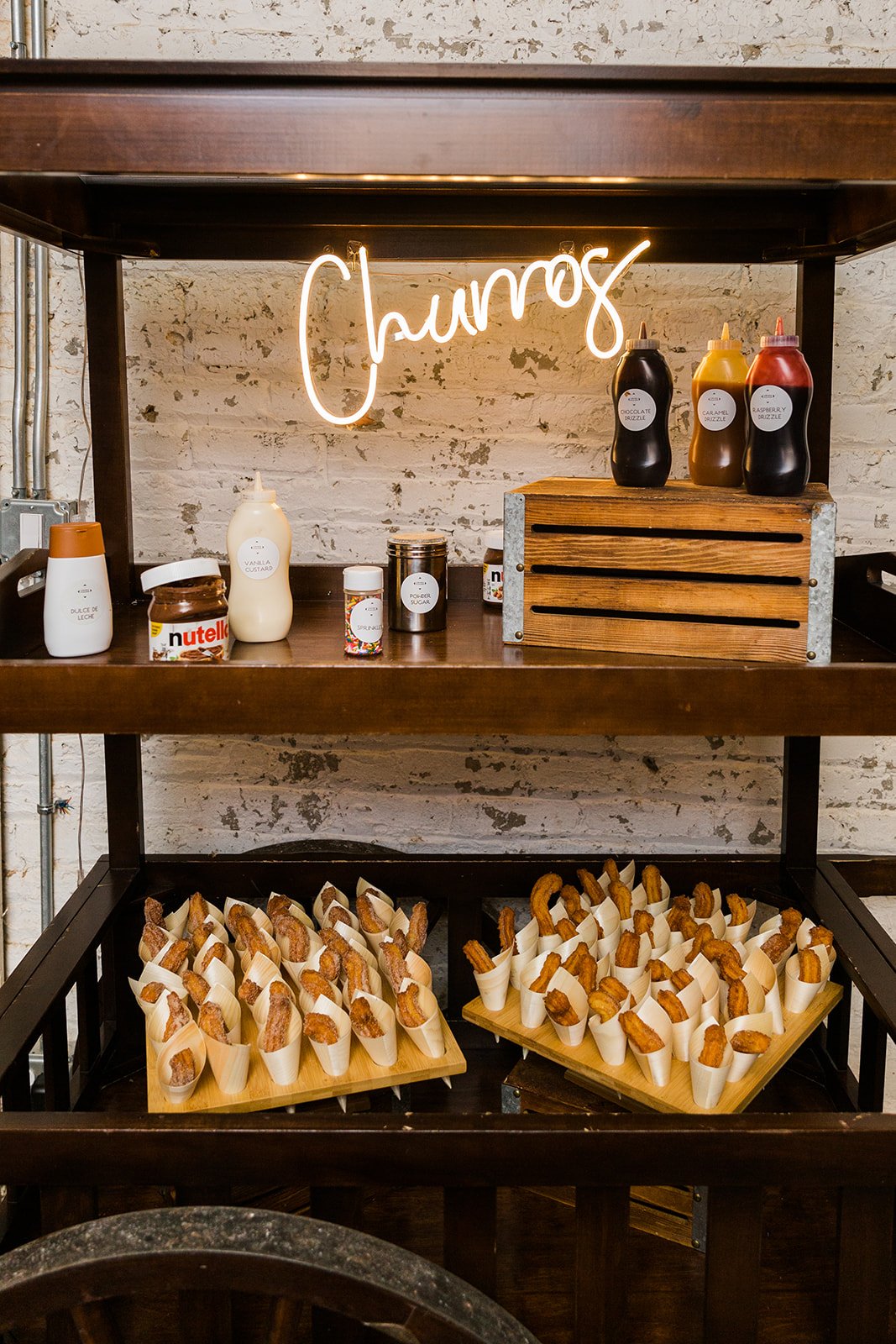  Detail photo of churros cart at reception at nontraditional Jewish and Venezuelan wedding at The Joinery Chicago an Industrial loft wedding venue In Logan Square.  