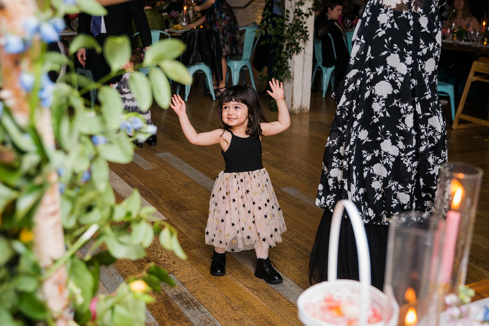  Documentary candid photo flower girl dancing during the reception at nontraditional Jewish and Venezuelan wedding at The Joinery Chicago an Industrial loft wedding venue In Logan Square.  