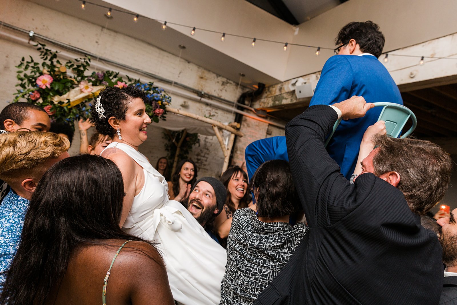  Documentary candid photo of the hora at nontraditional Jewish and Venezuelan wedding at The Joinery Chicago an Industrial loft wedding venue In Logan Square.  