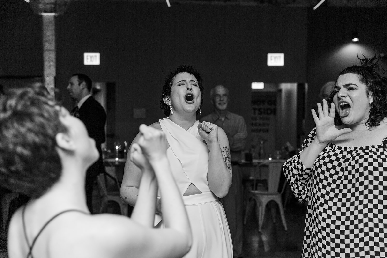  Black and white Documentary candid photo of guests dancing at nontraditional Jewish and Venezuelan wedding reception at The Joinery Chicago an Industrial loft wedding venue In Logan Square.  