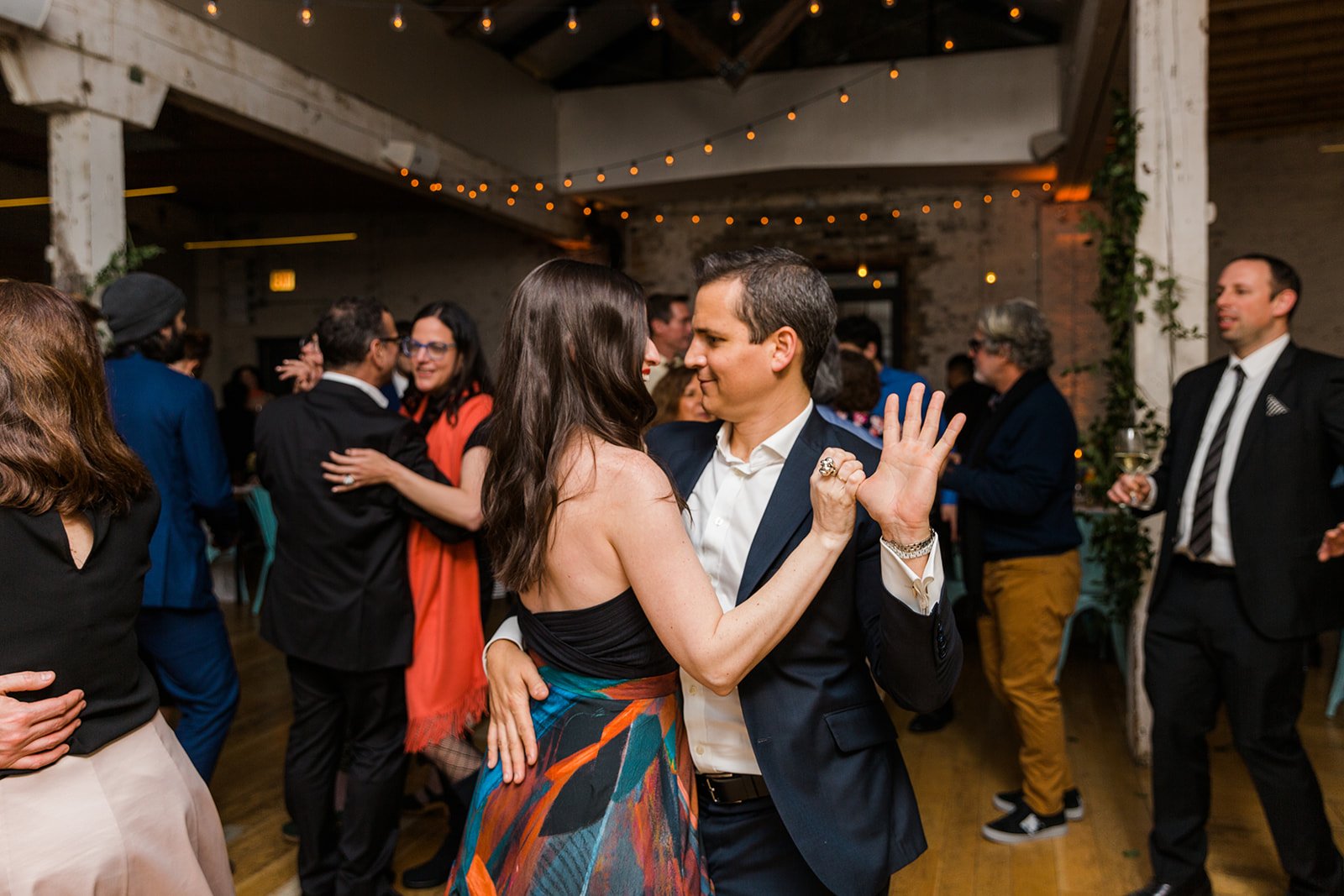  Documentary candid photo of guests dancing at nontraditional Jewish and Venezuelan wedding reception at The Joinery Chicago an Industrial loft wedding venue In Logan Square.  
