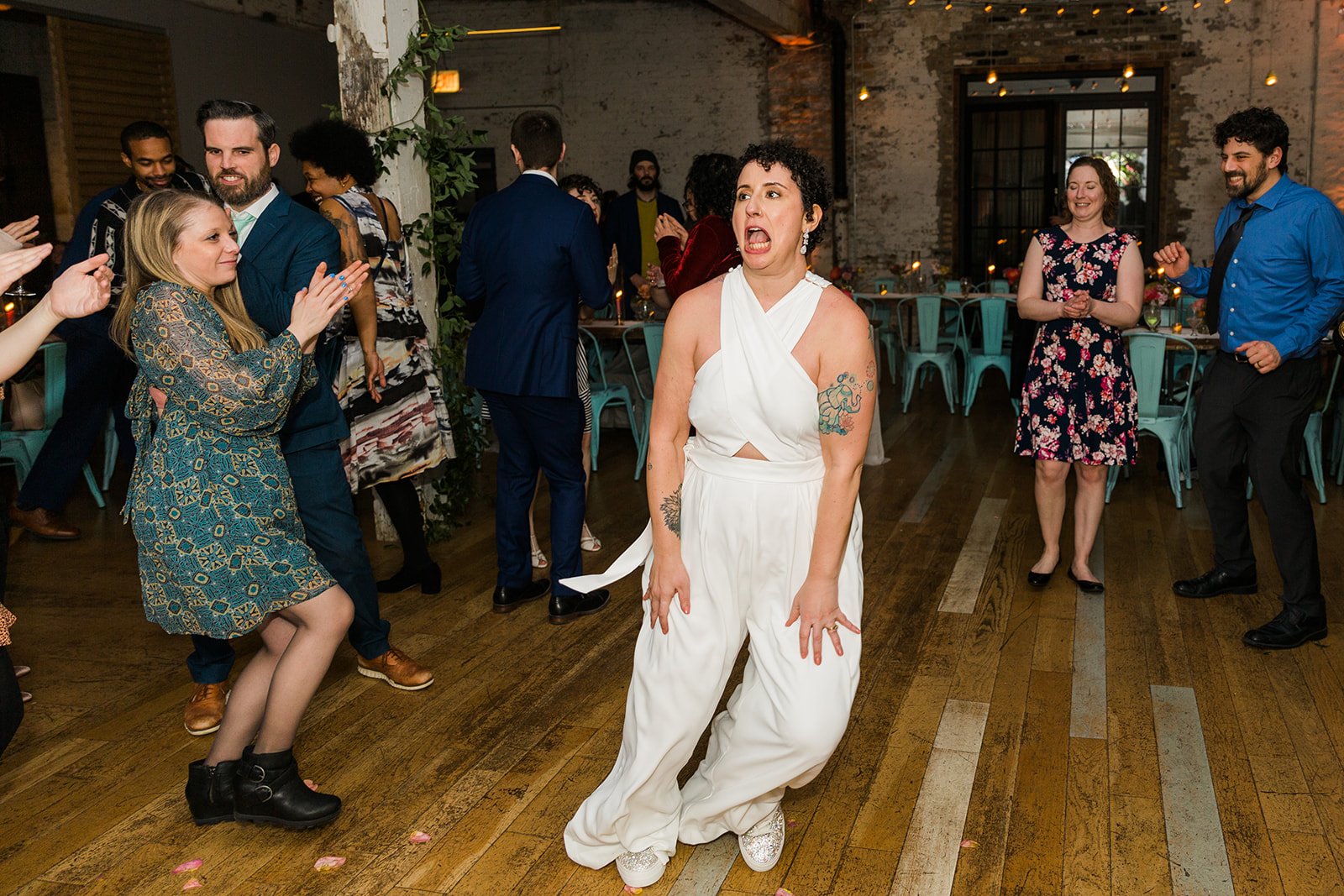 Documentary candid photo of bride dancing at nontraditional Jewish and Venezuelan wedding reception at The Joinery Chicago an Industrial loft wedding venue In Logan Square.  