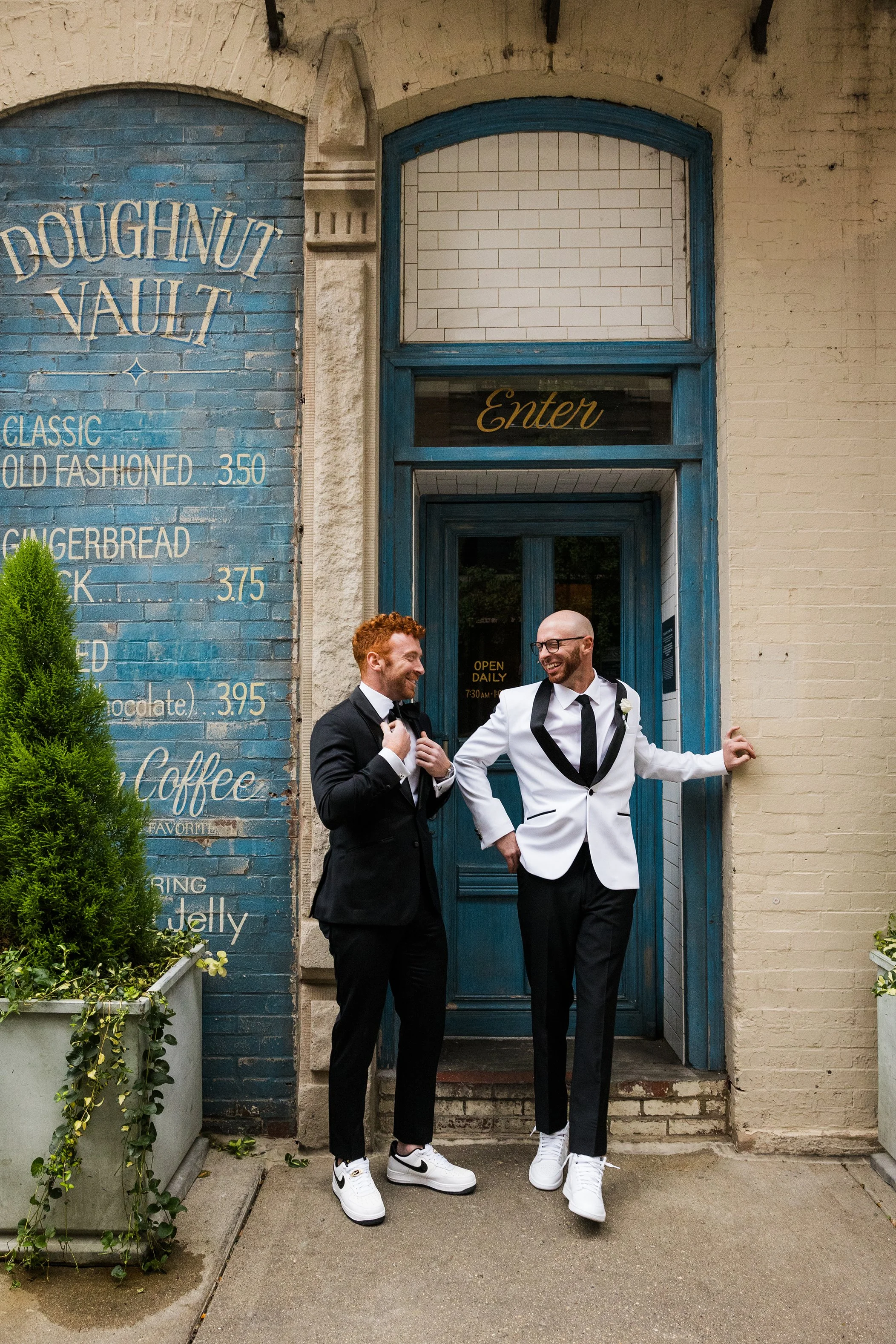  Documentary style candid of a groom in a black and white tux with his best man before family photos in front of he Doughnut Vault in Chicago. Gilt Bar wedding 