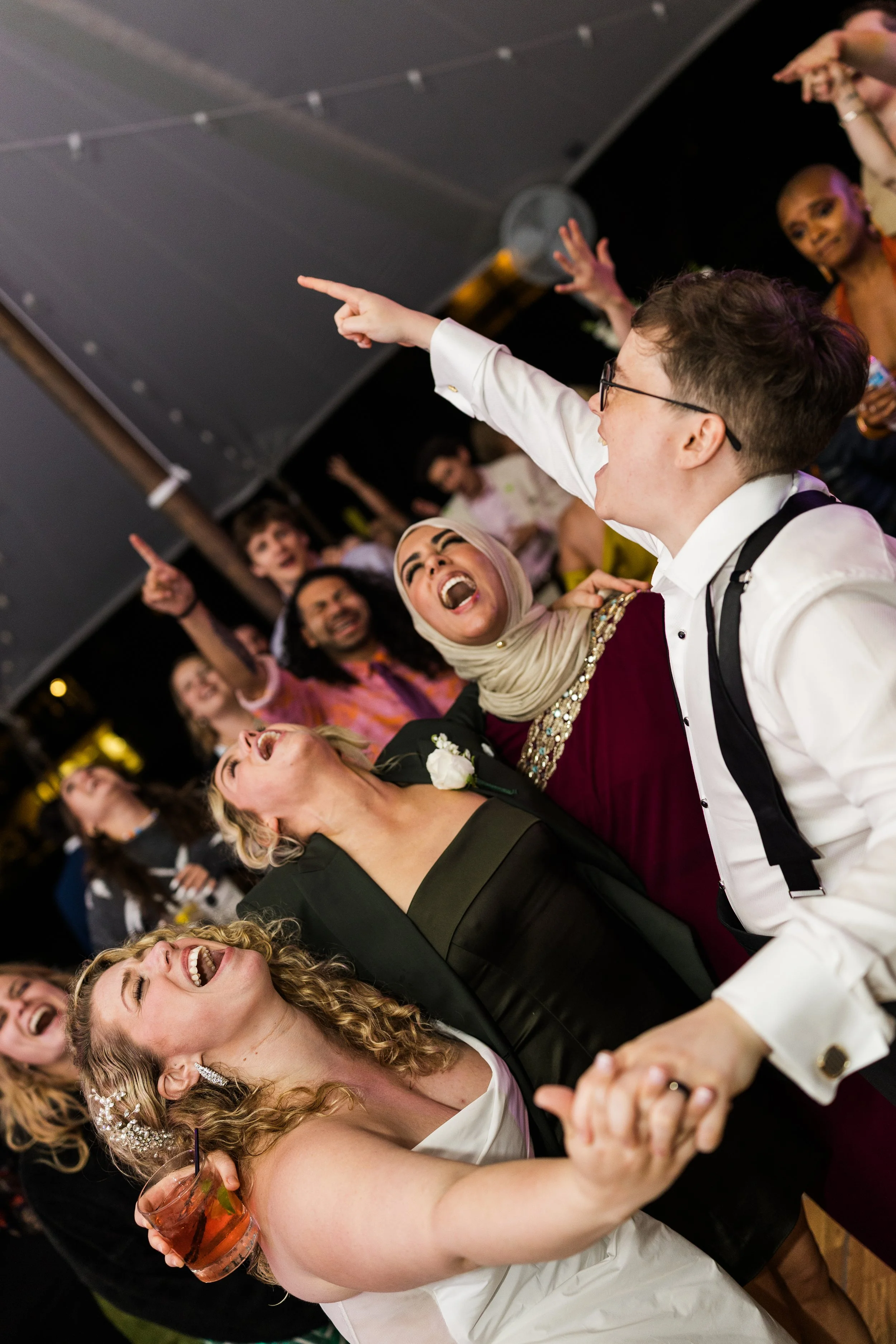 Documentary candid photo of queer multicultural wedding party dancing and singing