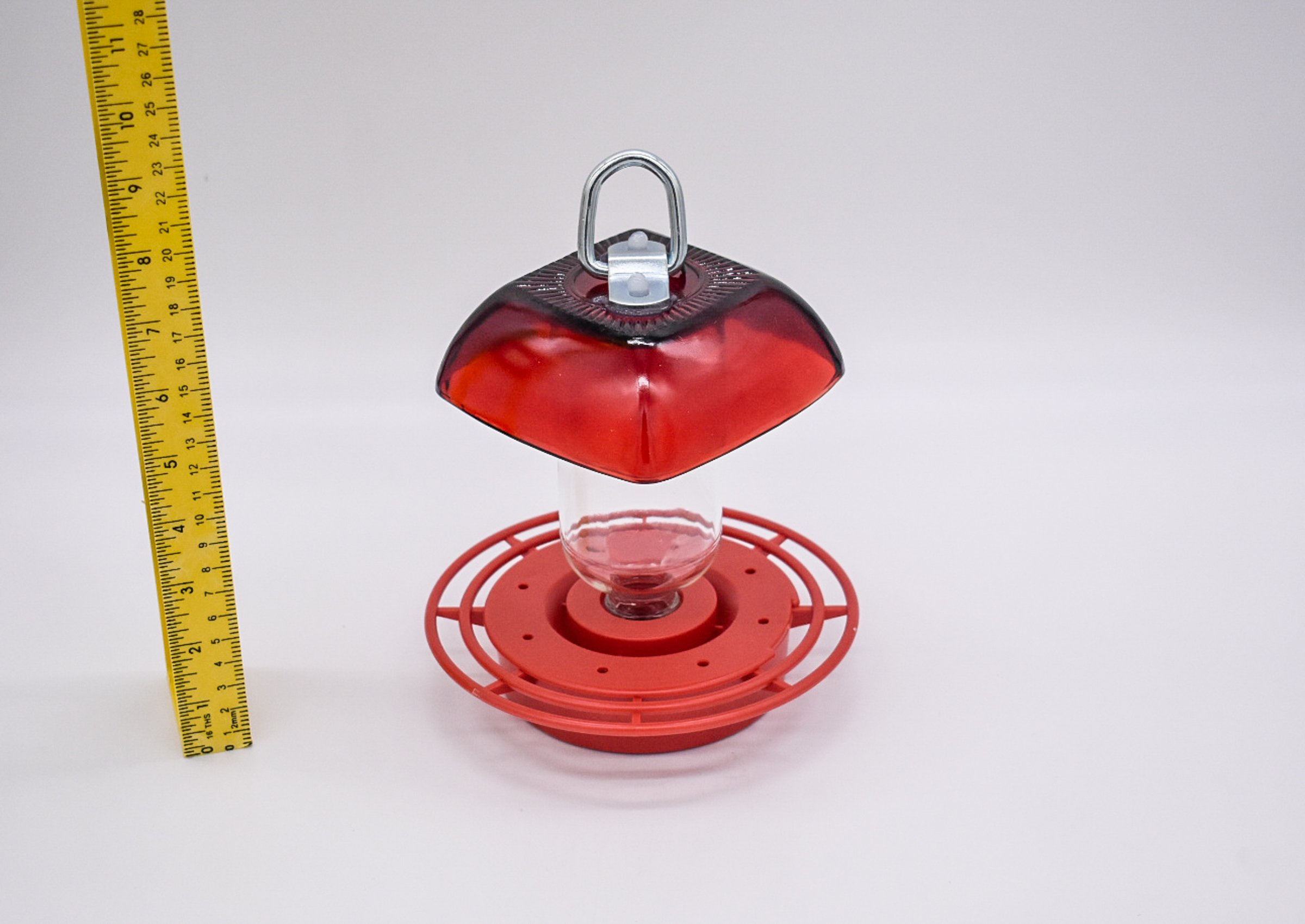 Side view of the Anchor Hocking Ruby Red Berry Bowl glass with 8 oz reservoir and red Best 1 plastic hummingbird feeder on a white background.