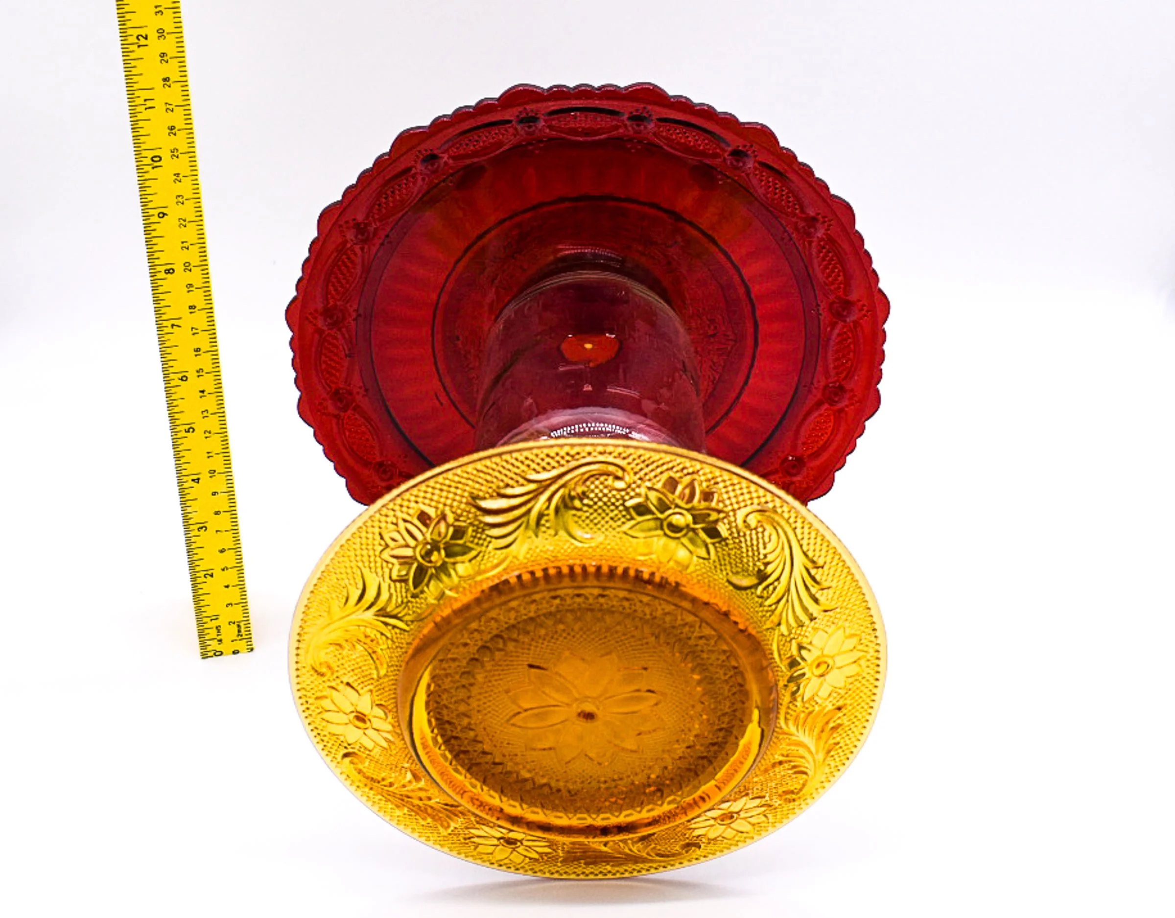 Underside view of the Avon Cape Cod ruby red glass plate and Indiana Tiara amber glass plate, highlighting their decorative vintage patterns.