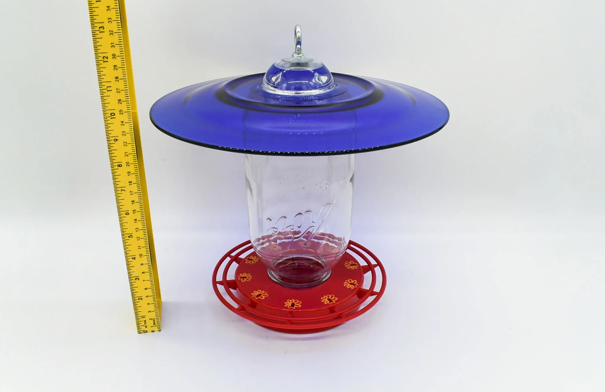 Angled view of the jumbo Mason jar feeder with cobalt blue glass and 10-station feeding base.