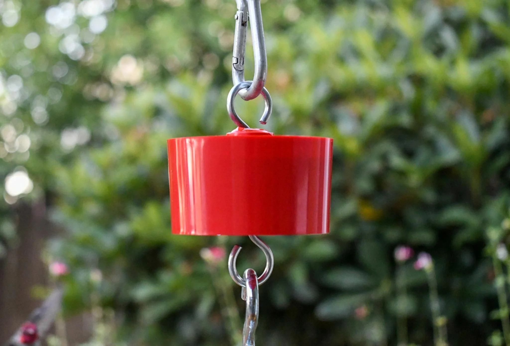Red Wildlife Accessories ant trap hanging outdoors to protect bird and hummingbird feeders from ants.
